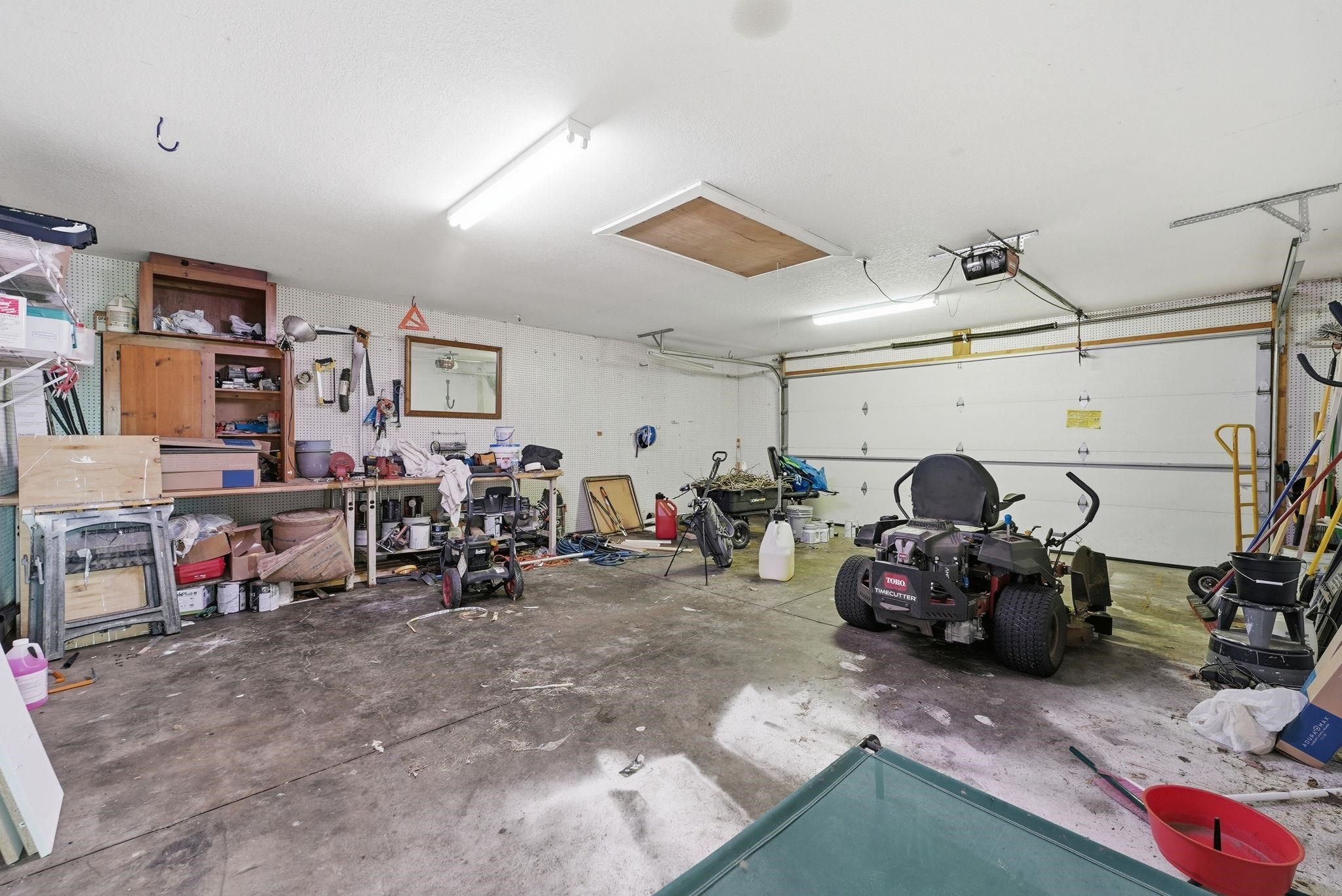 Attached garage with concrete flooring, overhead lighting, and an automatic garage door opener