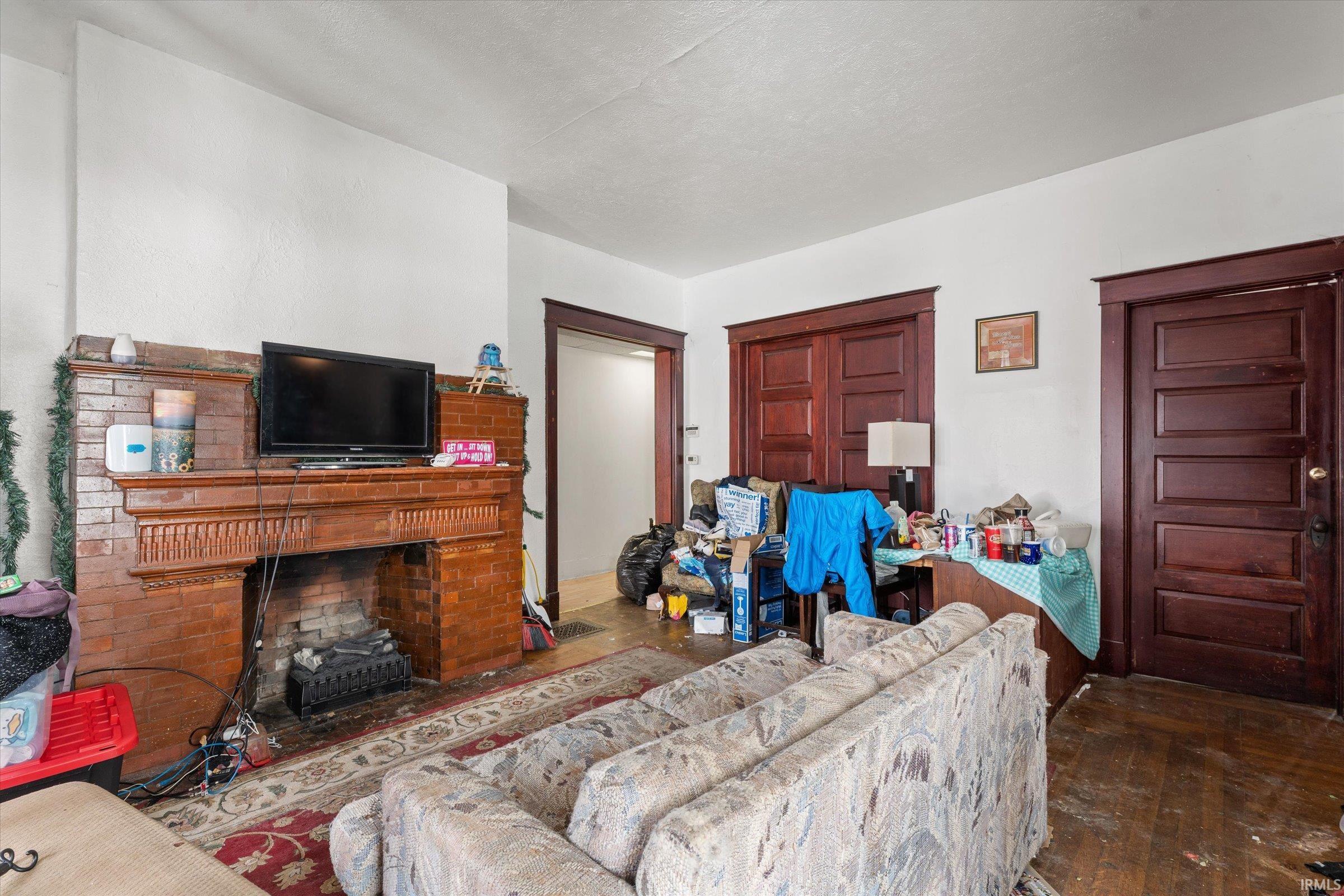 Living room featuring a brick fireplace and dark wood finished floors