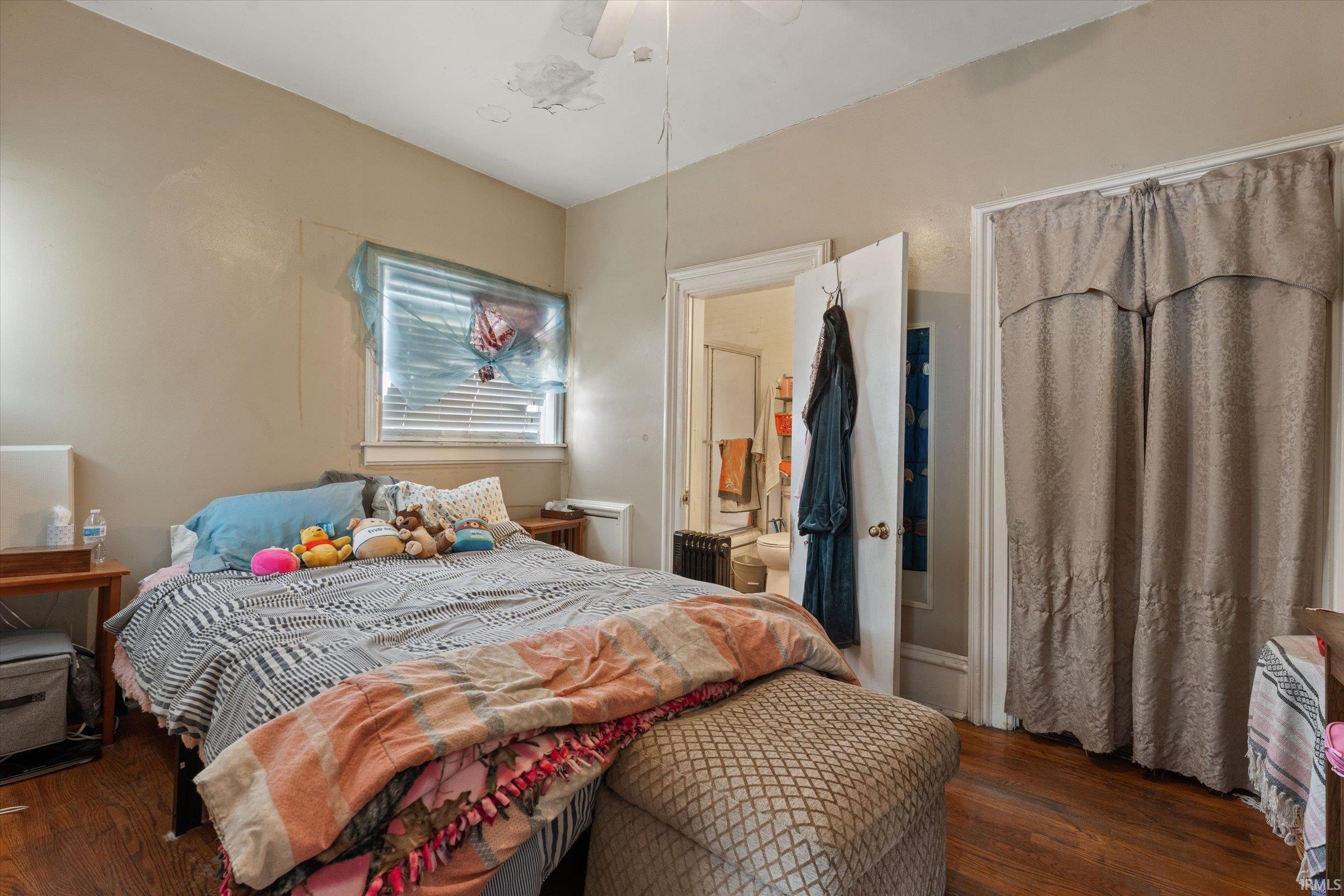 Bedroom with dark wood-style floors, connected bathroom, and a ceiling fan