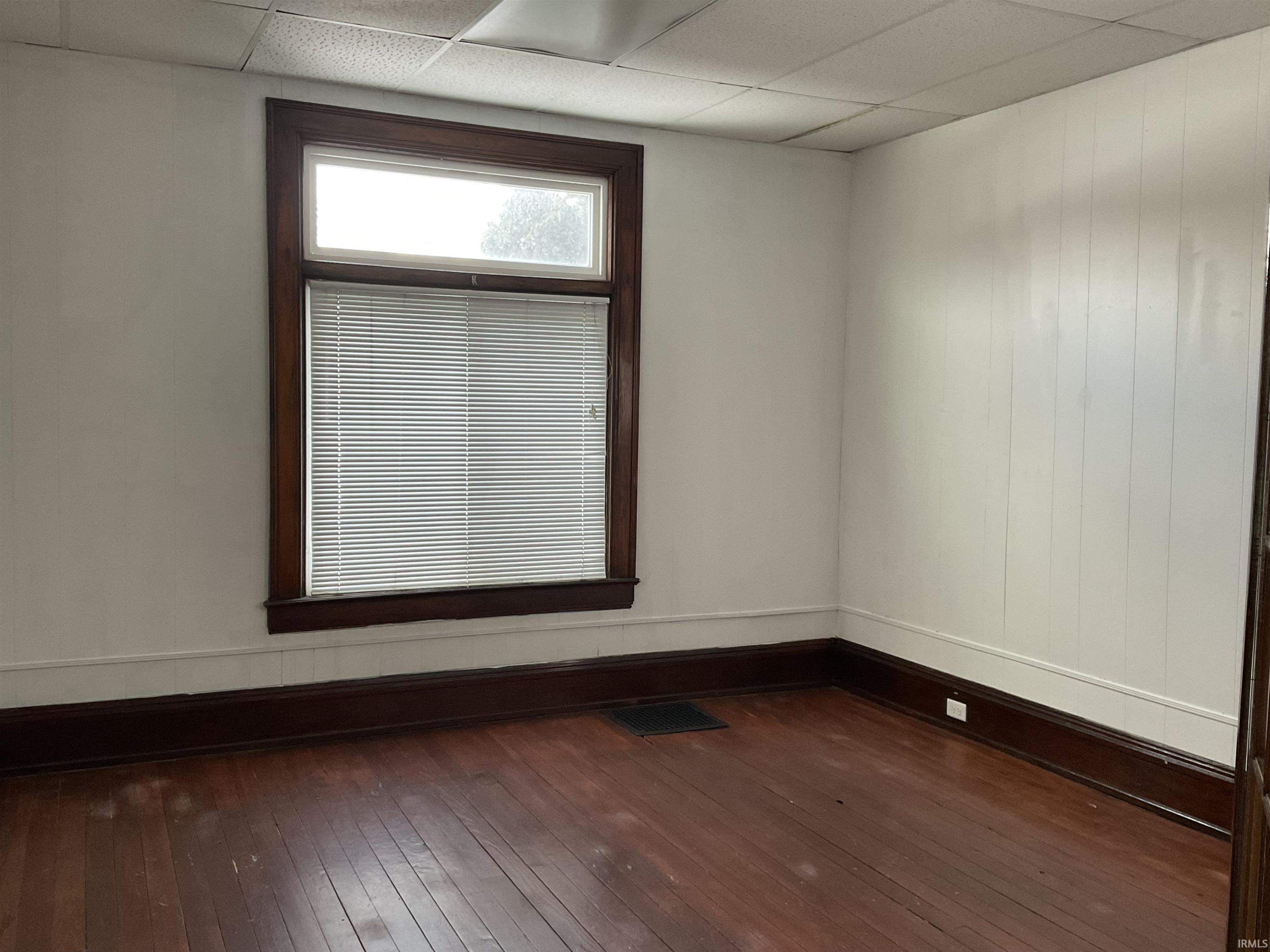 Spare room featuring dark wood finished floors and a drop ceiling