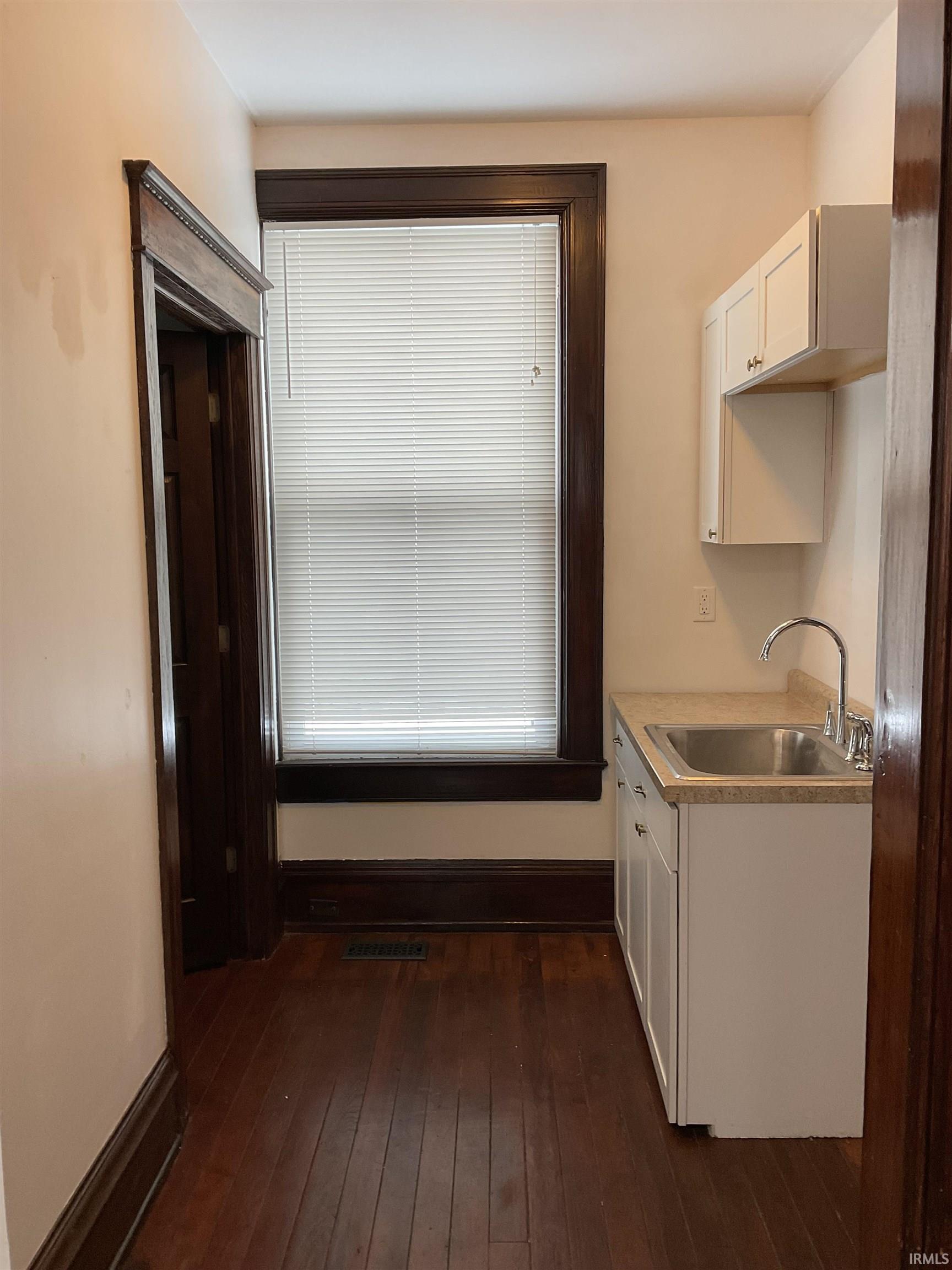 Kitchen featuring light countertops, white cabinetry, and dark wood flooring