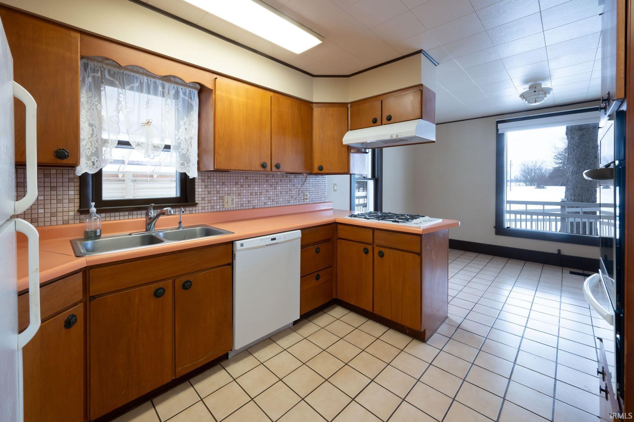 Kitchen with tasteful backsplash, brown cabinets, plenty of natural light, and light countertops