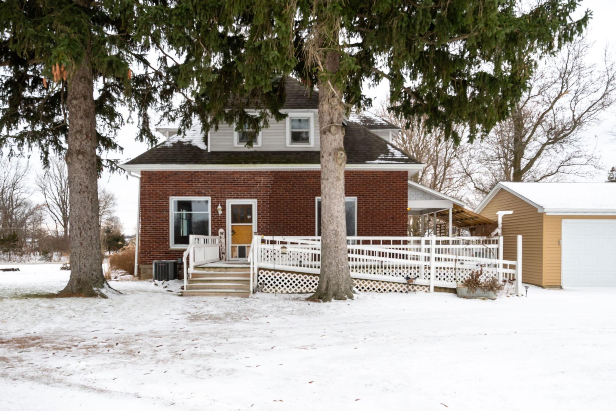 View of front of home with a wooden deck, an outbuilding, and brick siding