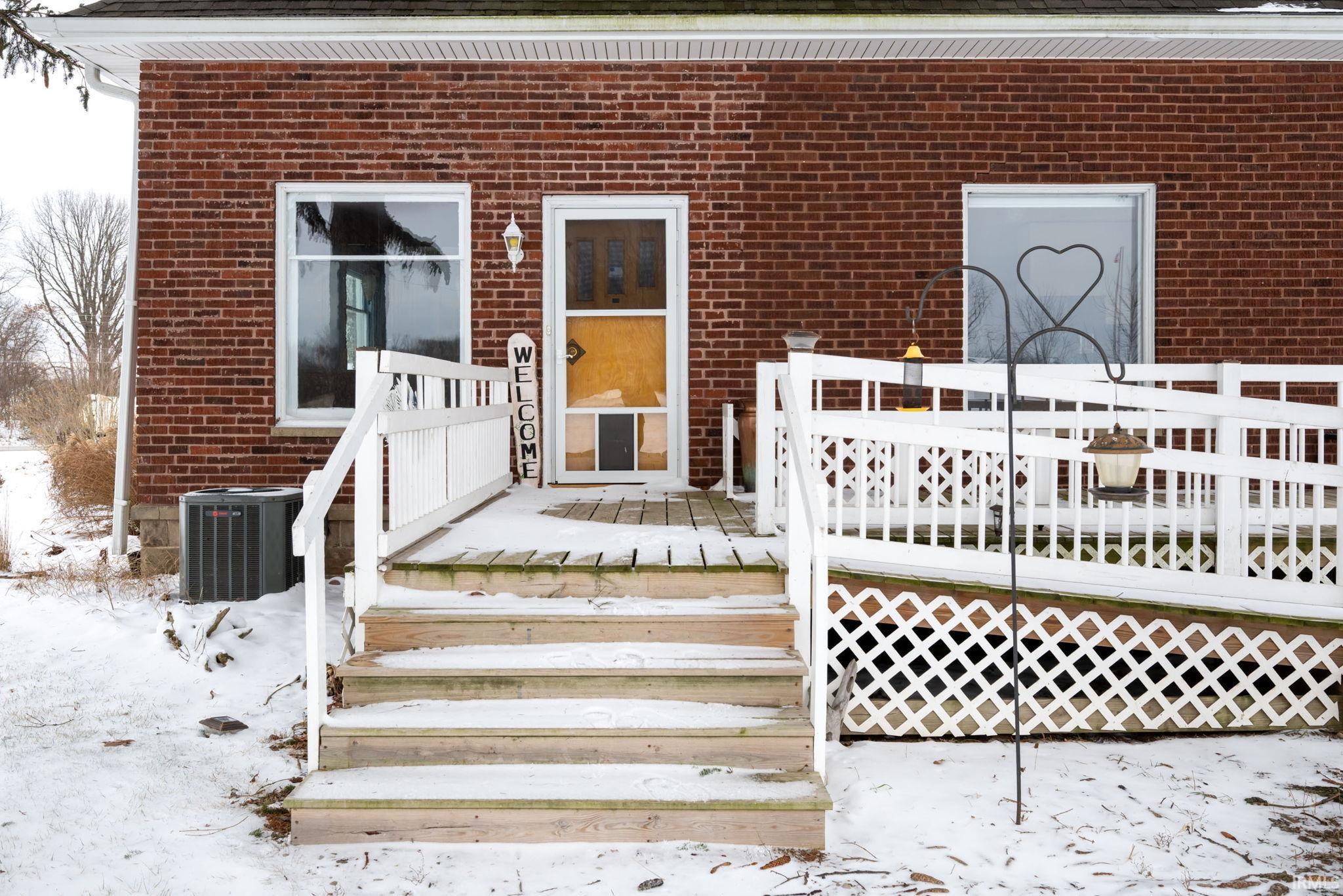Doorway to property with brick siding and a deck