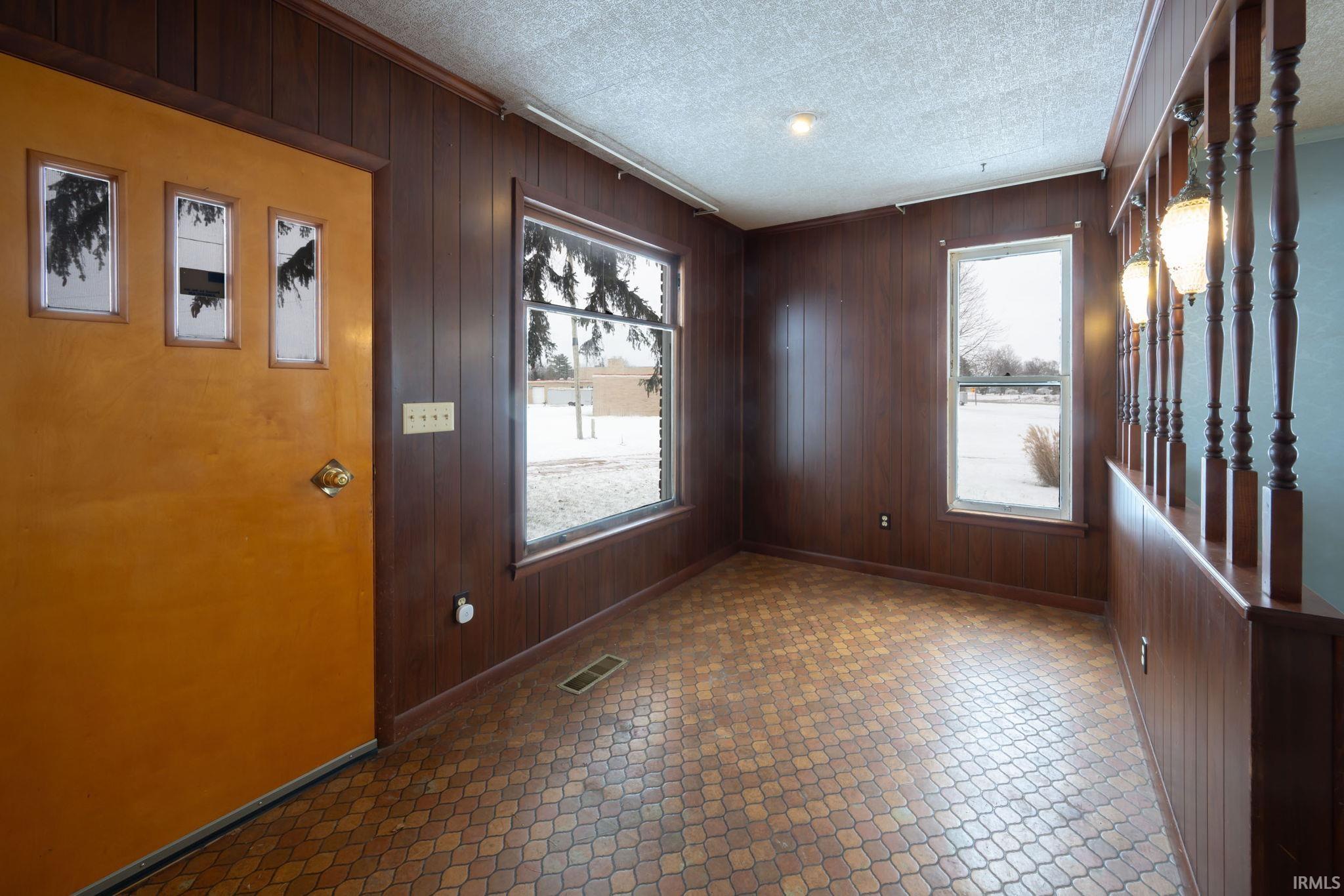 Foyer featuring wood walls, a textured ceiling, and plenty of natural light