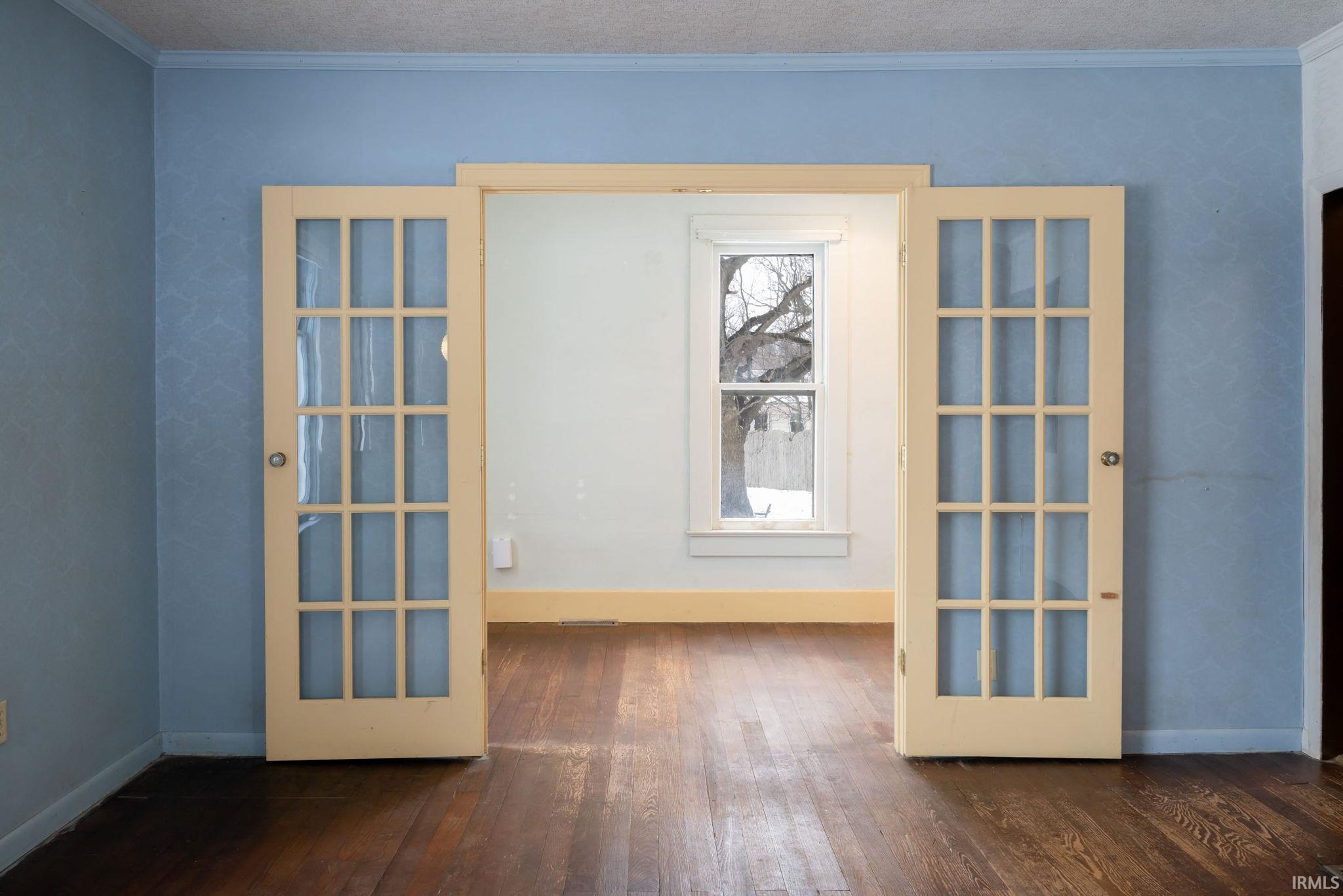 Empty room featuring crown molding and dark wood-style flooring