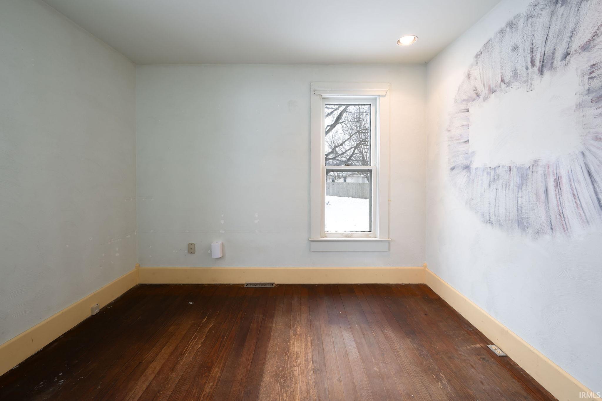 Unfurnished room featuring baseboards and dark wood-style flooring