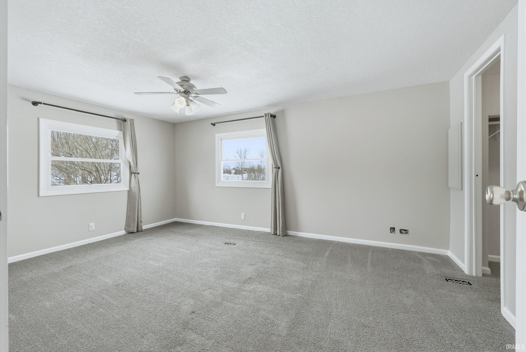 Empty room with a textured ceiling, carpet flooring, and ceiling fan