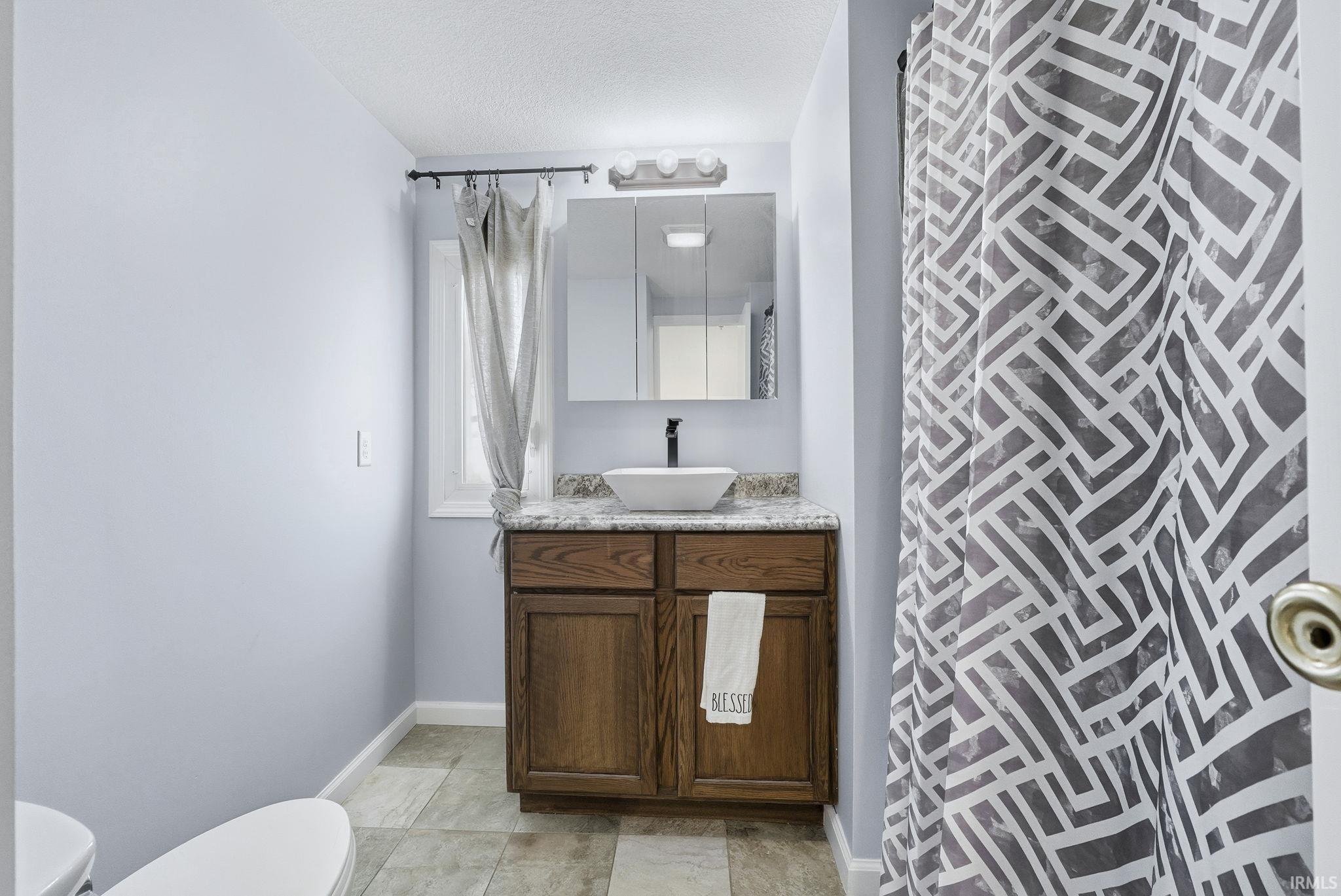 Full bathroom with vanity, a textured ceiling, and a shower with curtain