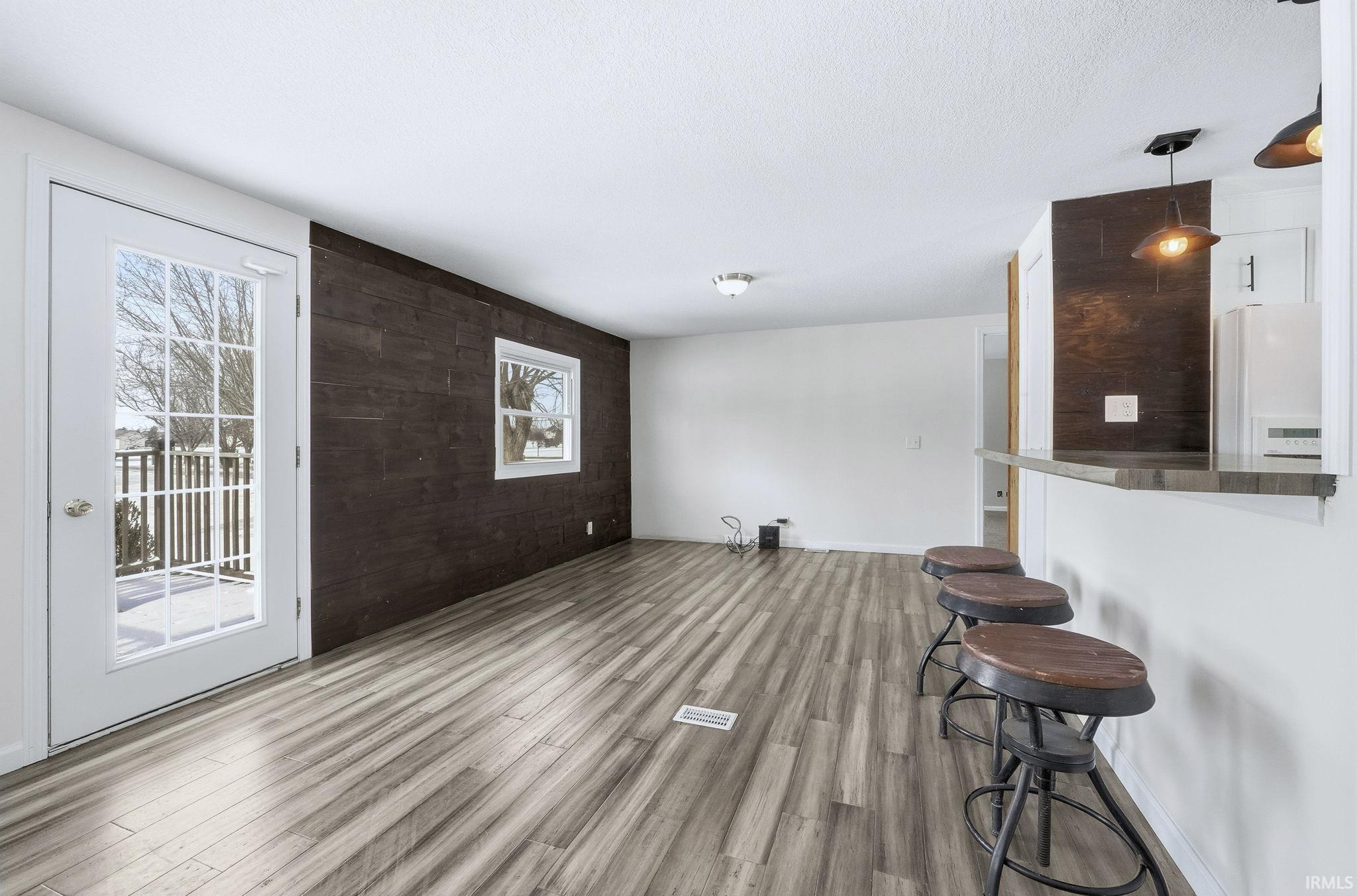 Unfurnished living room featuring an accent wall, wood finished floors, and a textured ceiling