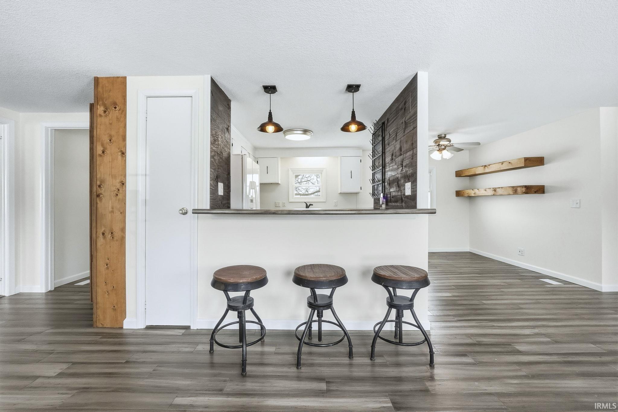 Kitchen with white cabinets, dark countertops, ceiling fan, dark wood-type flooring, and a textured ceiling