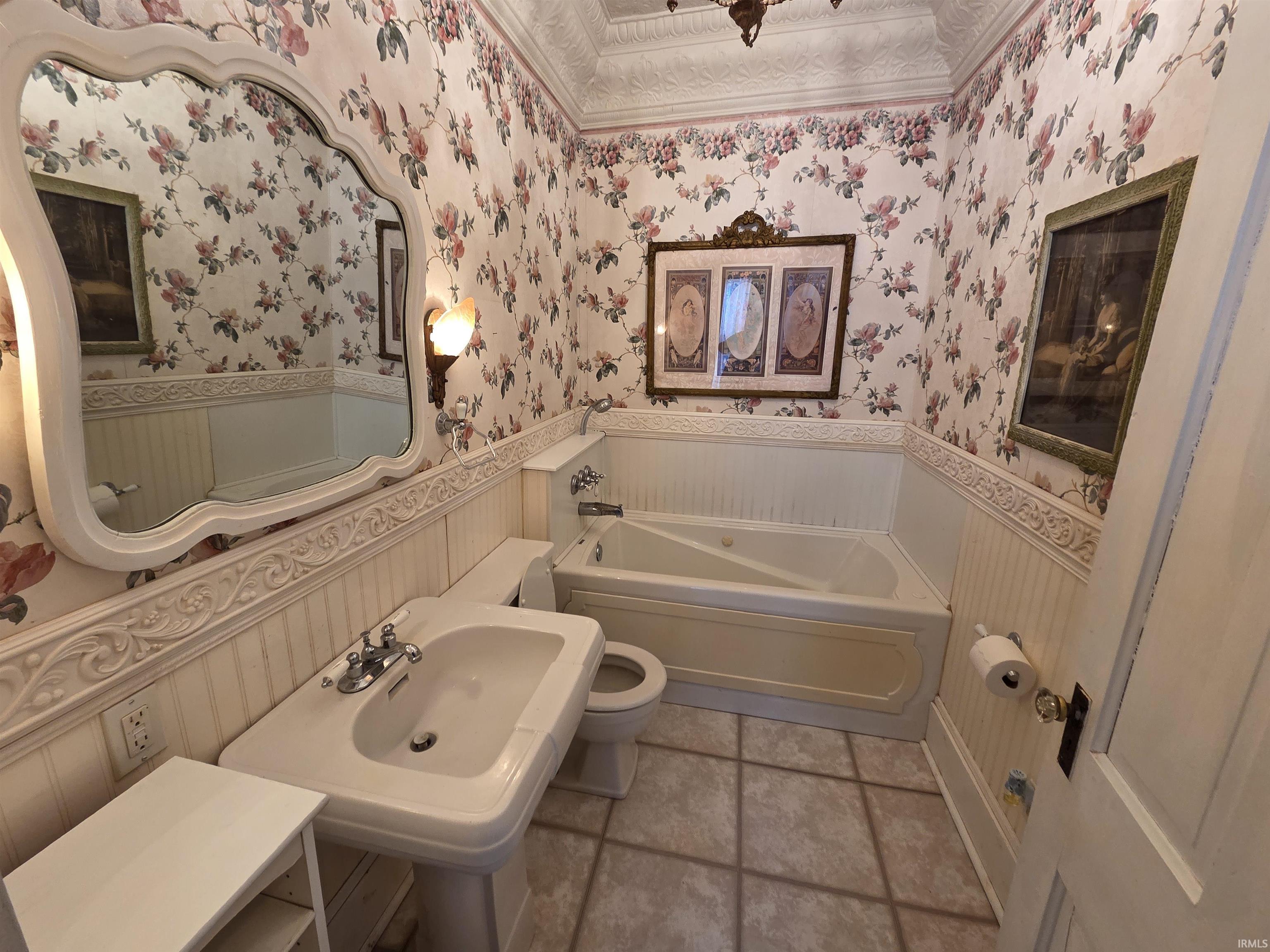 Bathroom featuring a wainscoted wall, a bath, wallpapered walls, ornamental molding, and a decorative wall