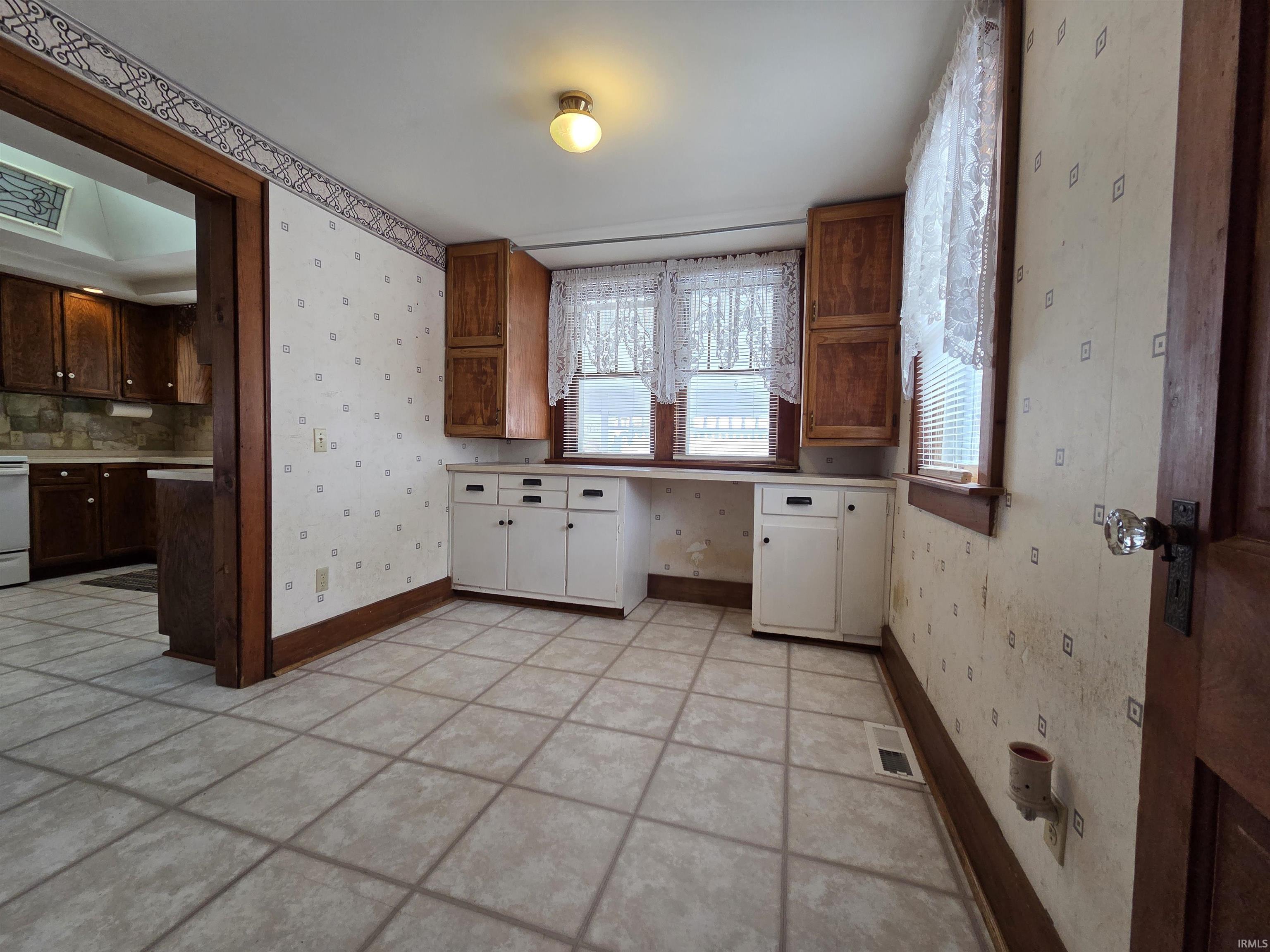 Kitchen with wallpapered walls, light tile patterned floors, light countertops, and white range with electric stovetop