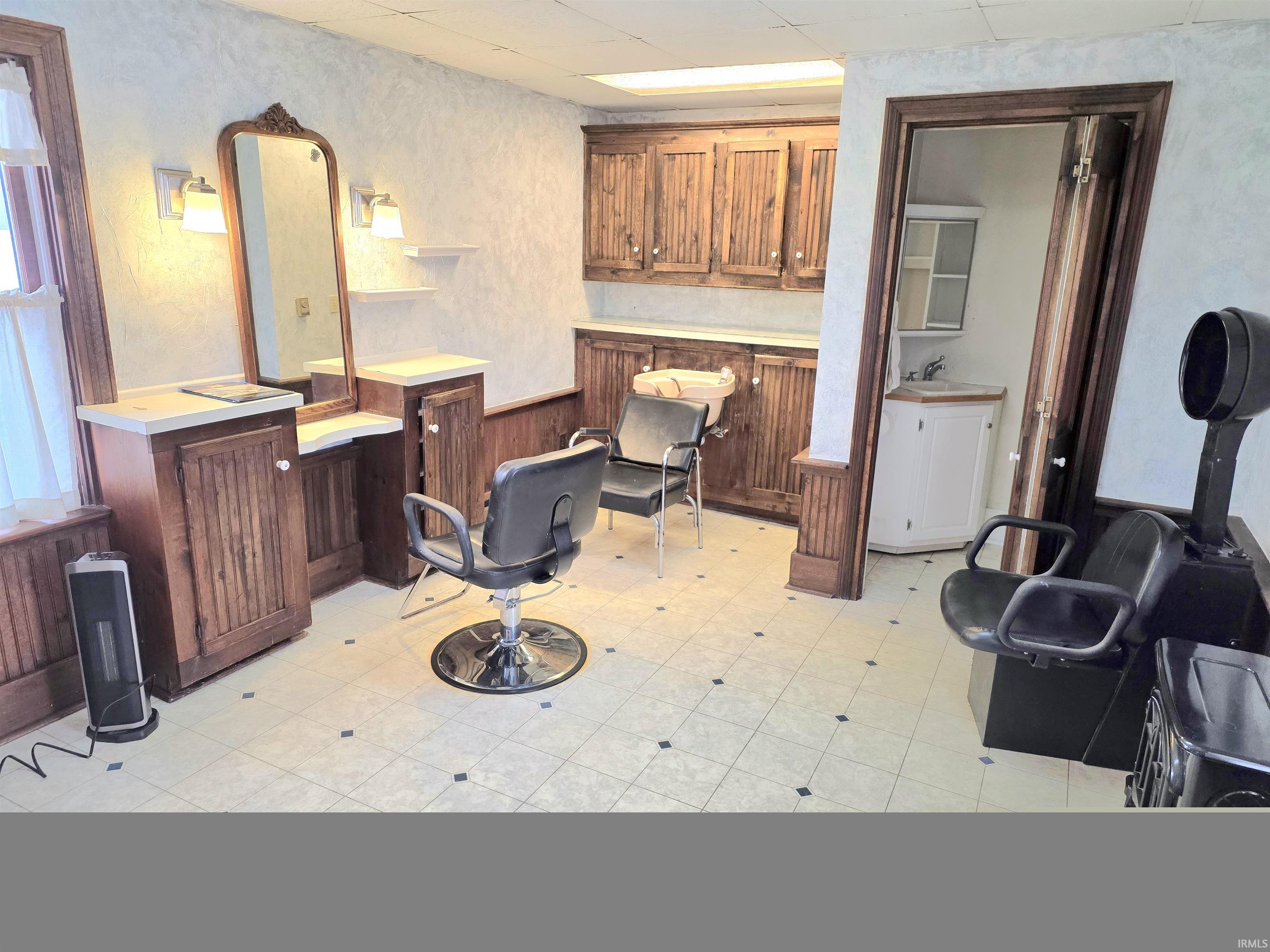 Misc room featuring light flooring, a wainscoted wall, wooden walls, and a paneled ceiling