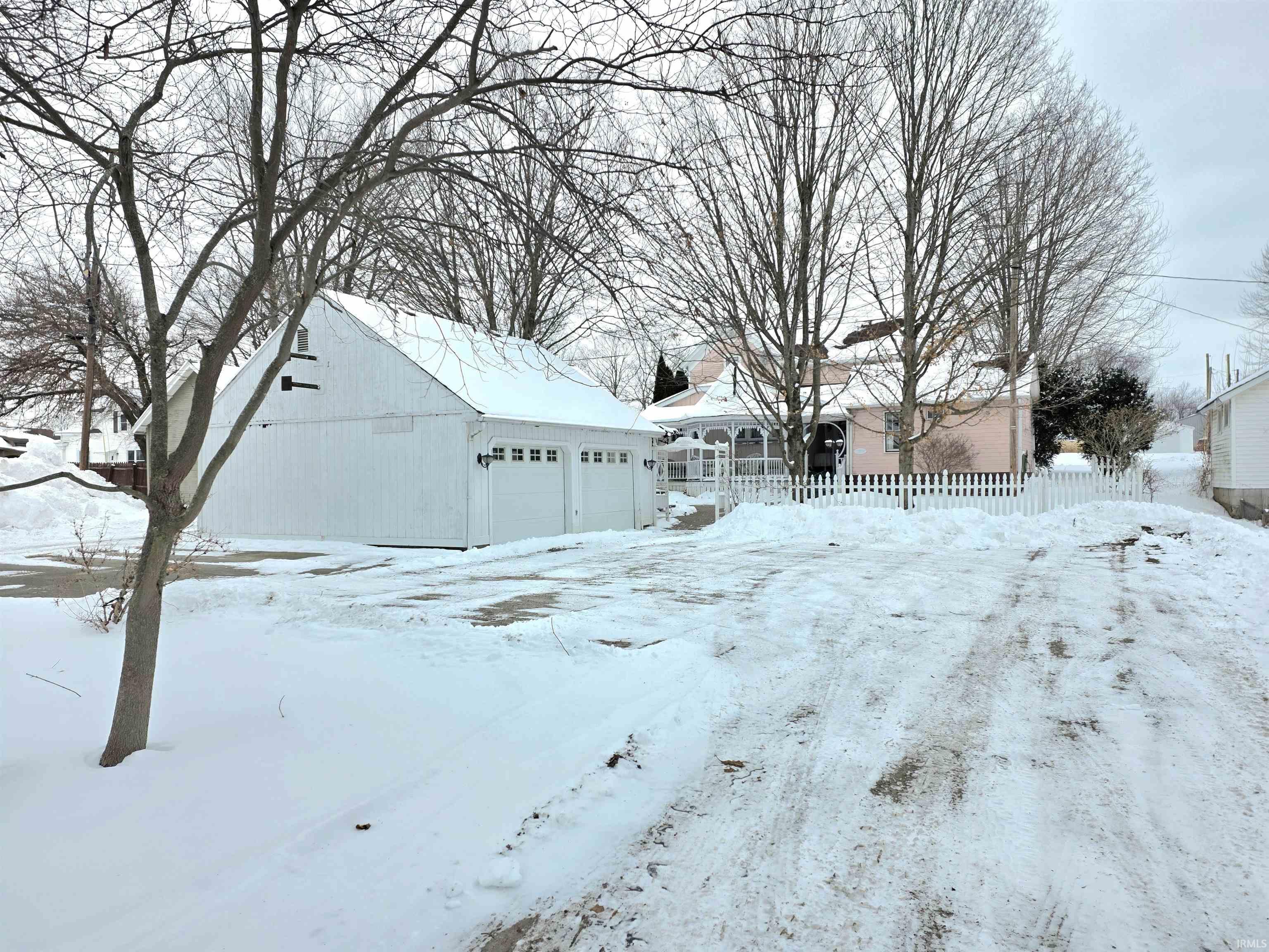 Yard layered in snow with a garage and an outdoor structure