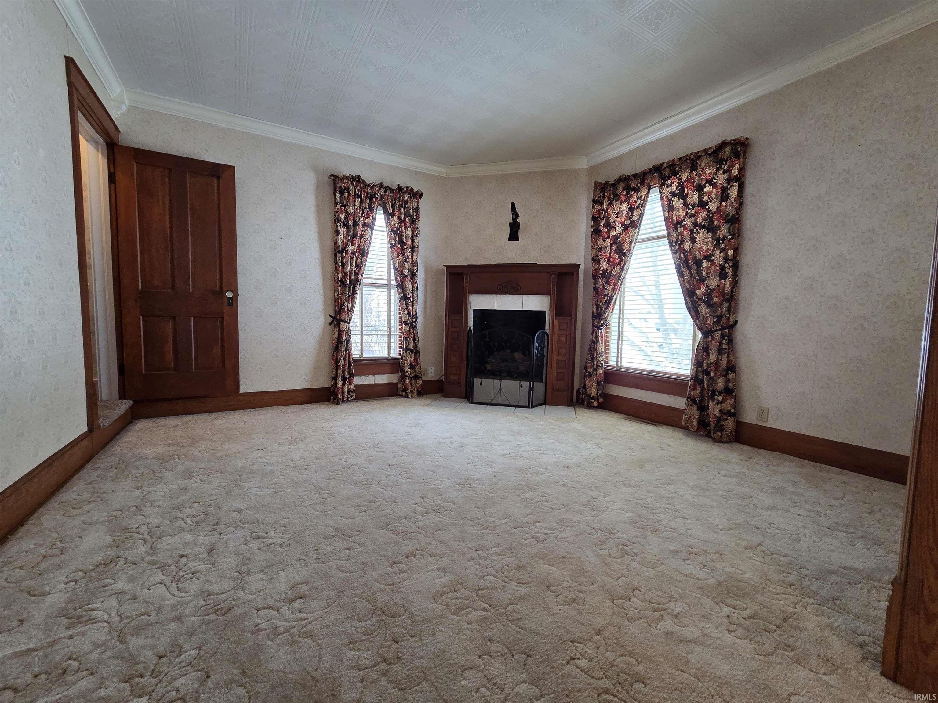 Unfurnished living room with an ornate ceiling, a fireplace, carpet, and ornamental molding