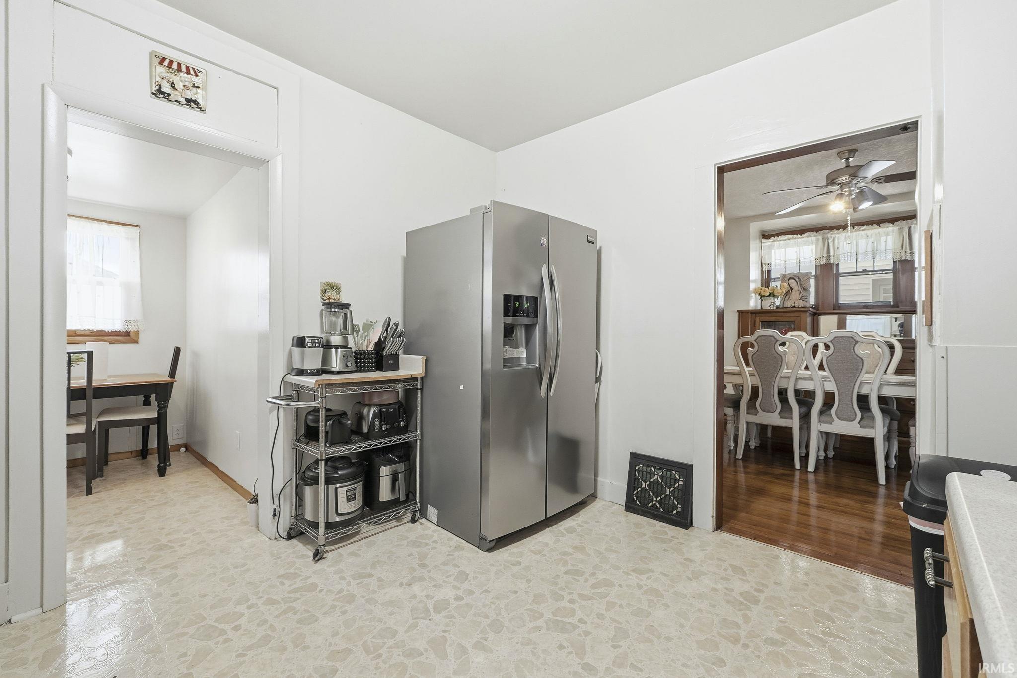 Kitchen with stainless steel fridge with ice dispenser, stone floors, and ceiling fan