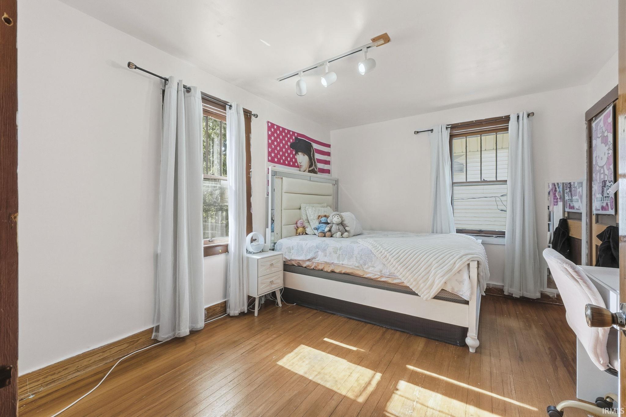 Bedroom featuring hardwood / wood-style floors, track lighting, and multiple windows