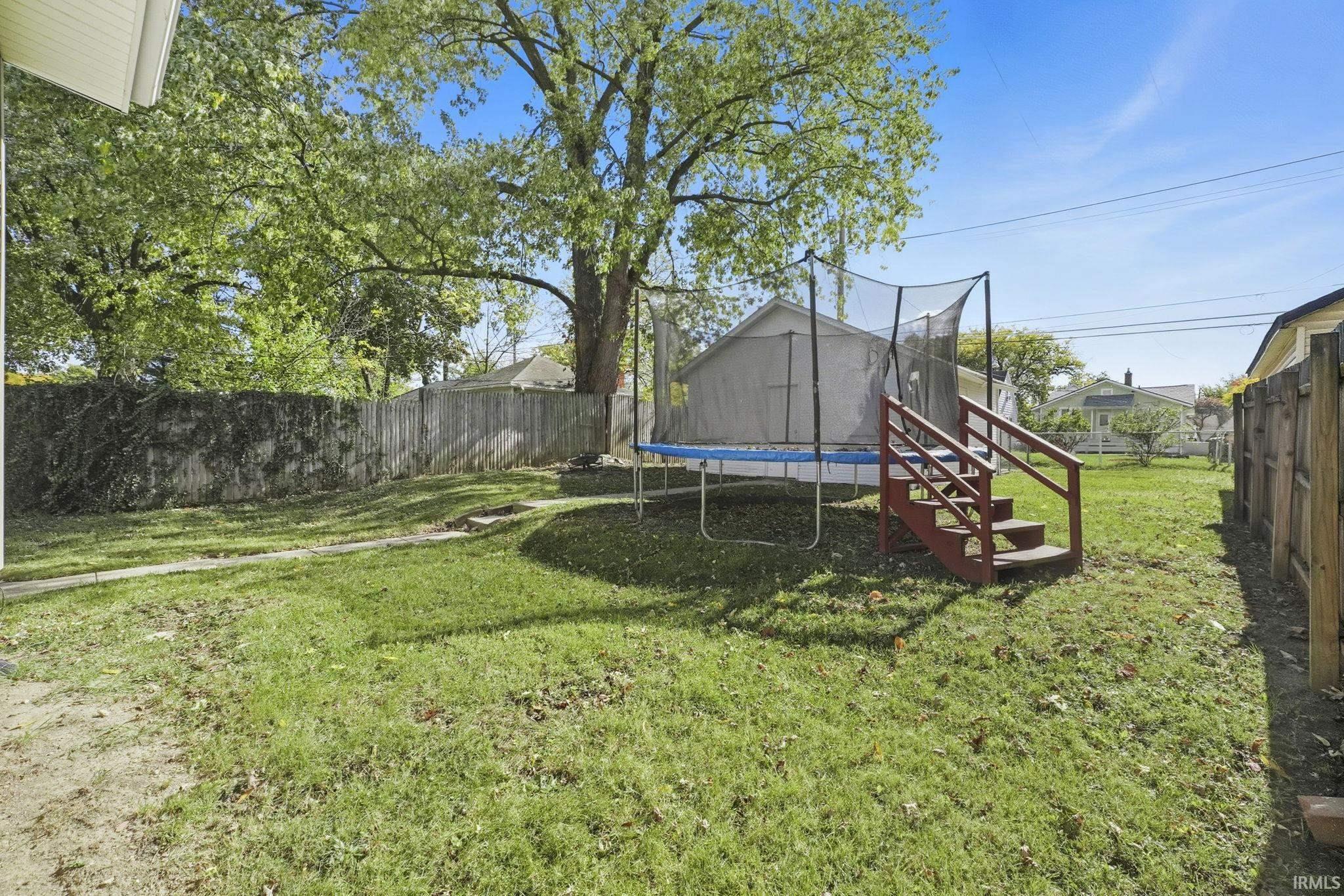 Fenced backyard featuring a trampoline