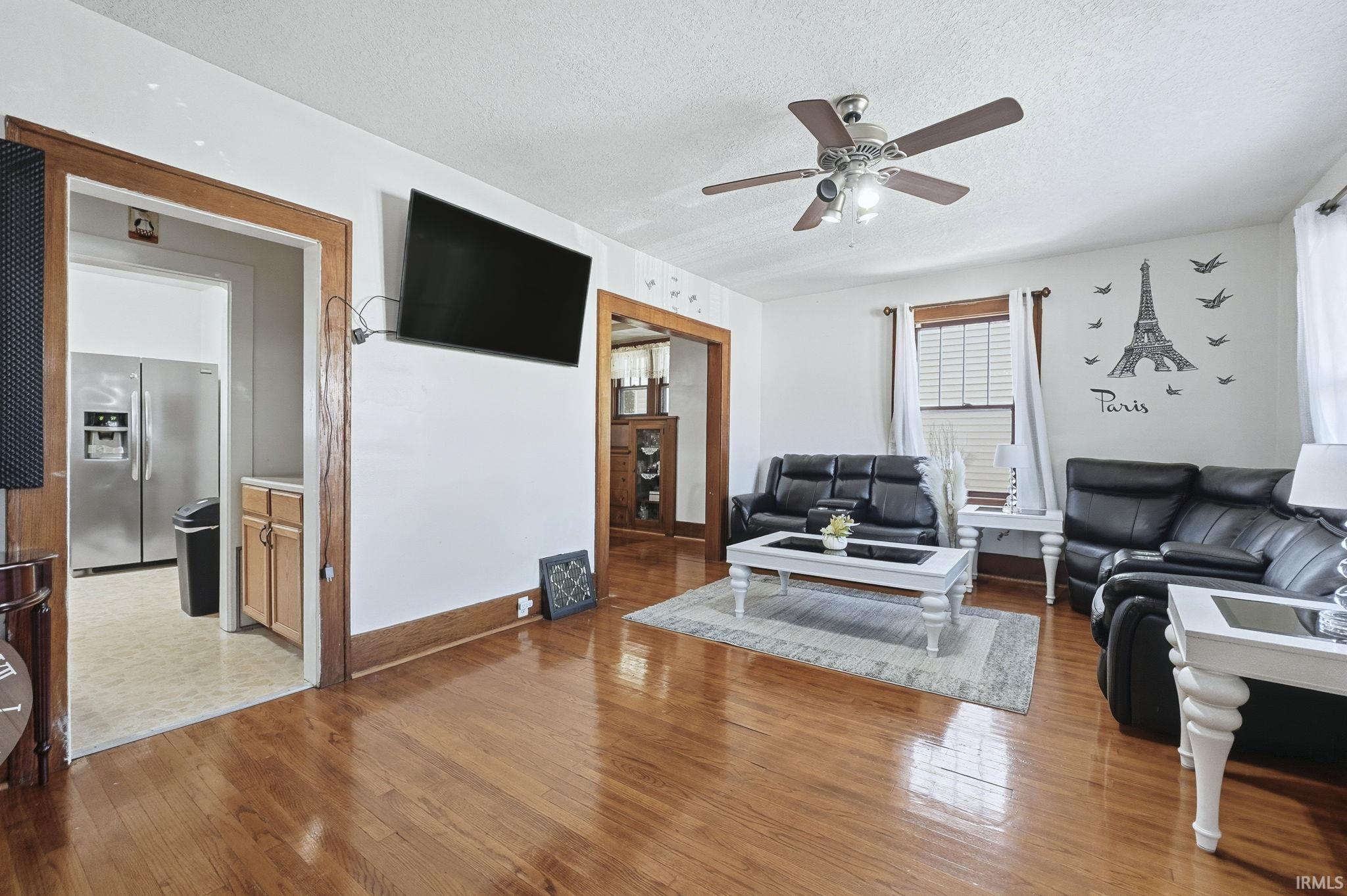 Living room featuring a textured ceiling, light wood-style flooring, and a ceiling fan