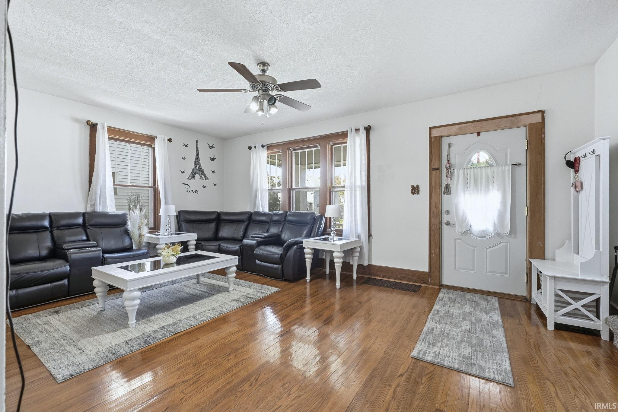 Living area featuring hardwood / wood-style flooring, a textured ceiling, and a ceiling fan