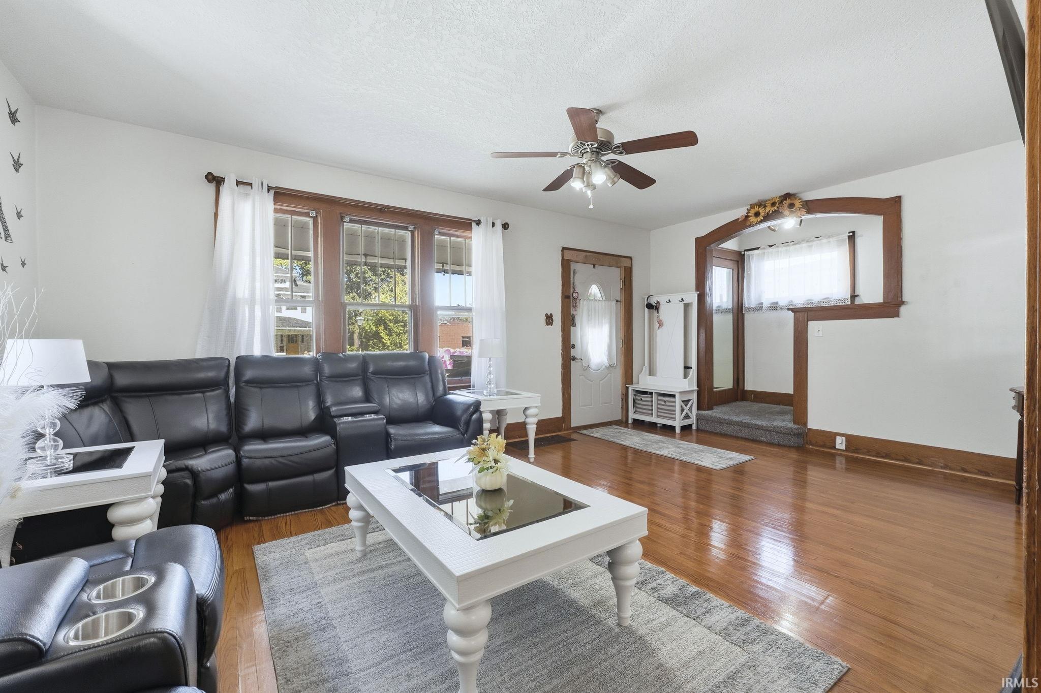Living room with hardwood / wood-style floors, a ceiling fan, and plenty of natural light