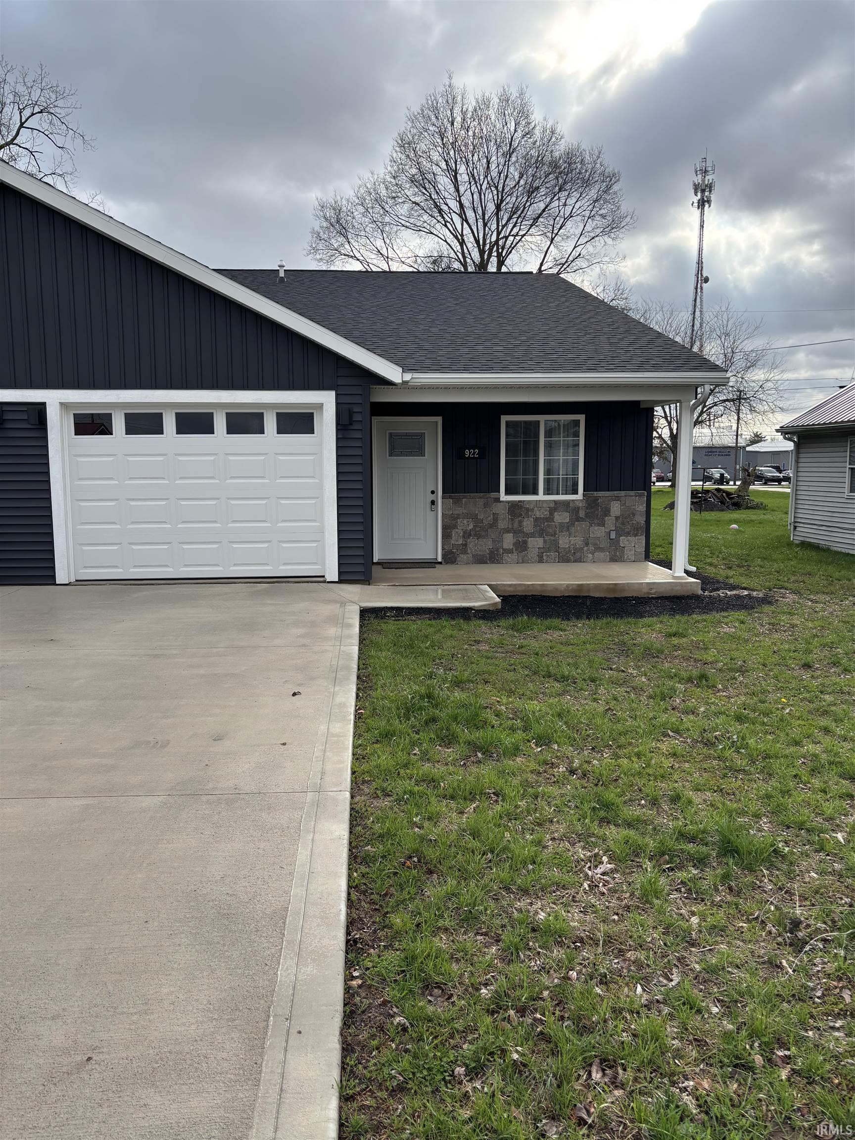 View of front of house with a porch, a front yard, roof with shingles, concrete driveway, and an attached garage
