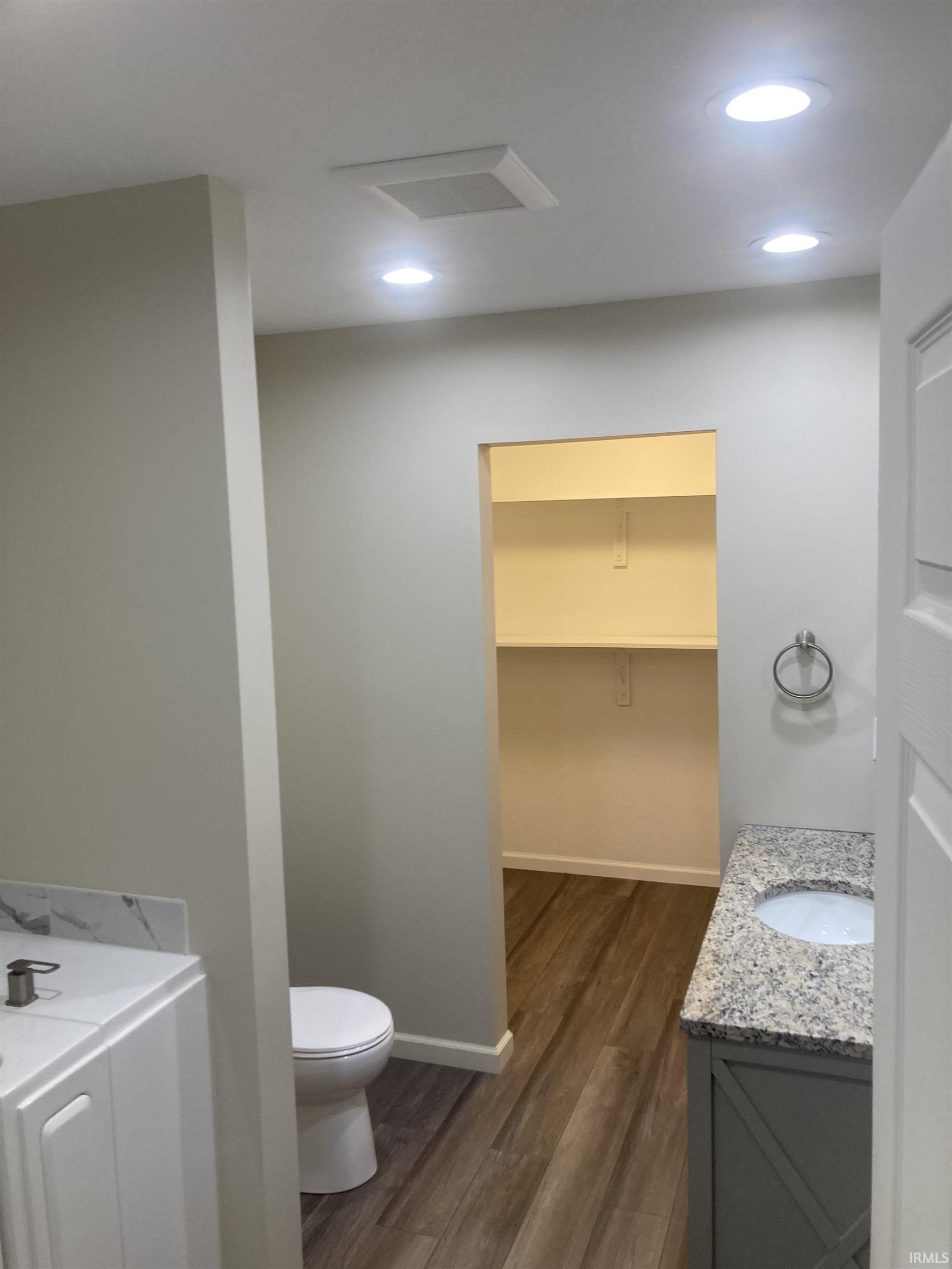 Full bath with vanity, dark wood-style flooring, a walk in closet, and recessed lighting