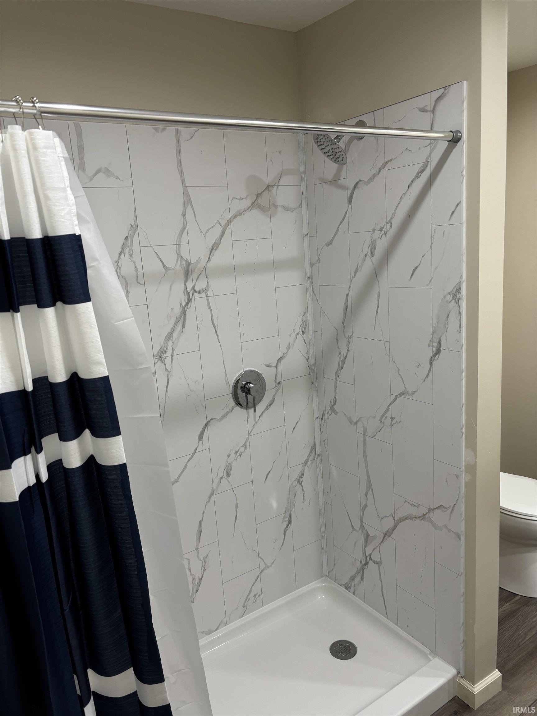 Full bathroom featuring a stall shower and toilet