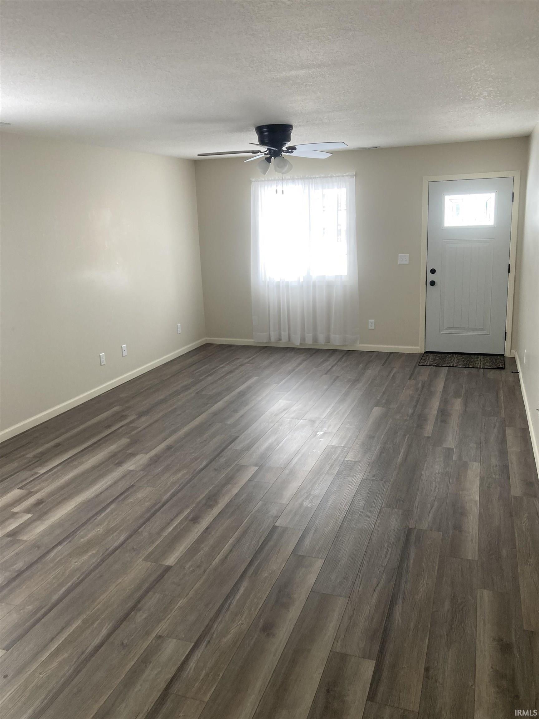 Entrance foyer featuring dark wood-style floors, a textured ceiling, and a ceiling fan