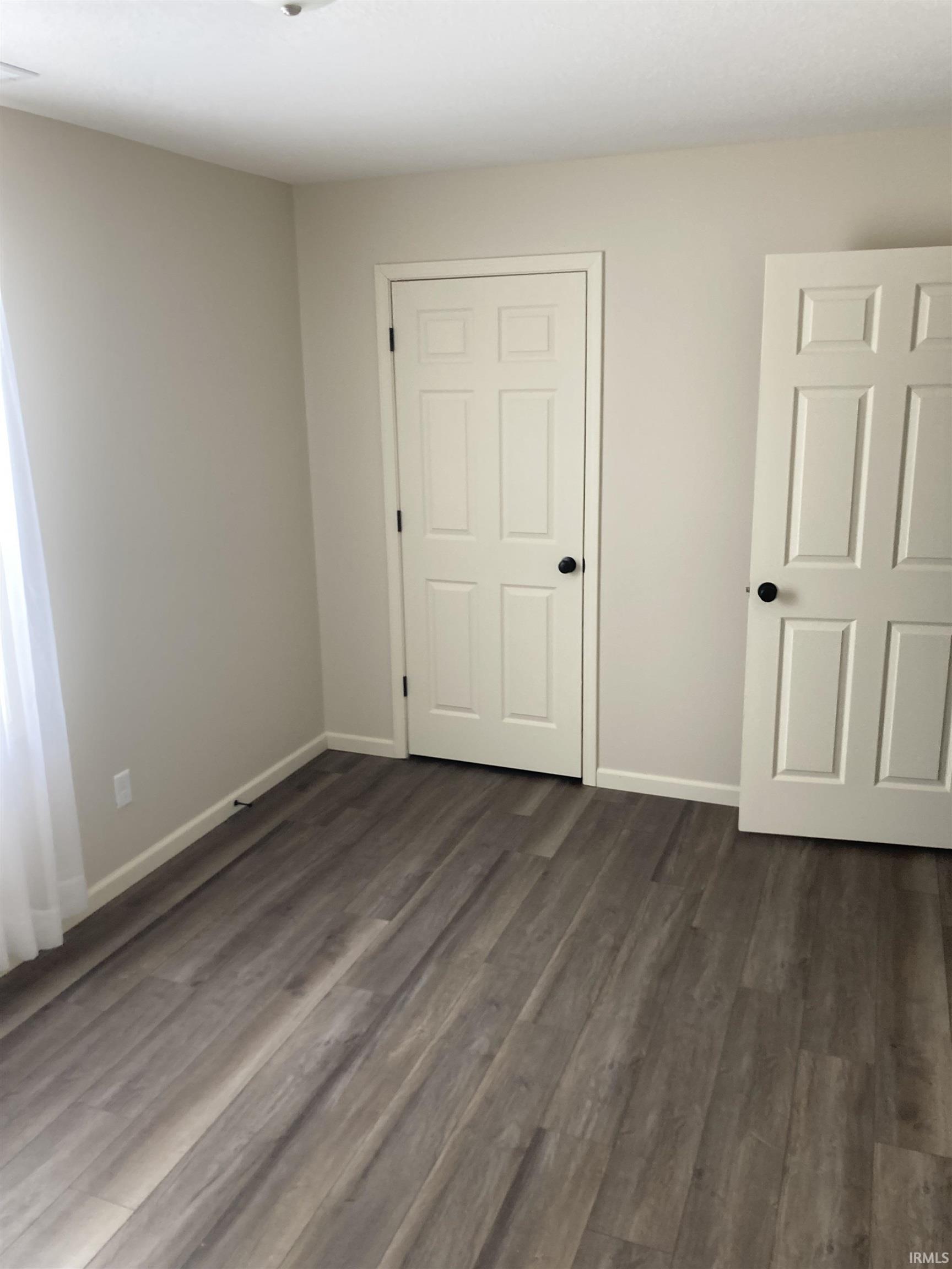 Unfurnished bedroom featuring dark wood finished floors and baseboards