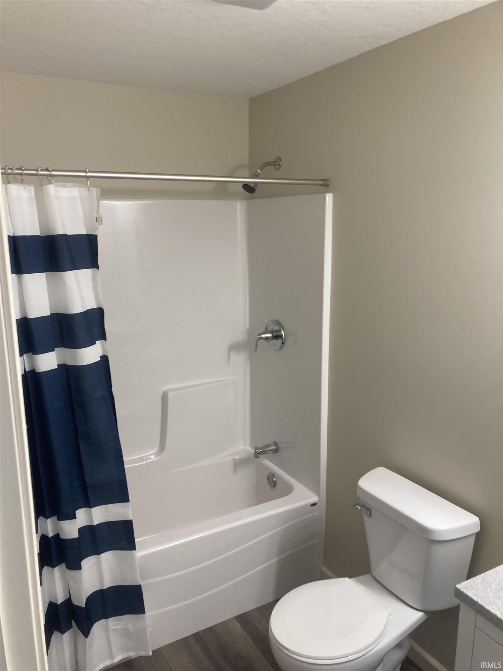 Full bath with vanity, shower / bath combo with shower curtain, and dark wood-type flooring