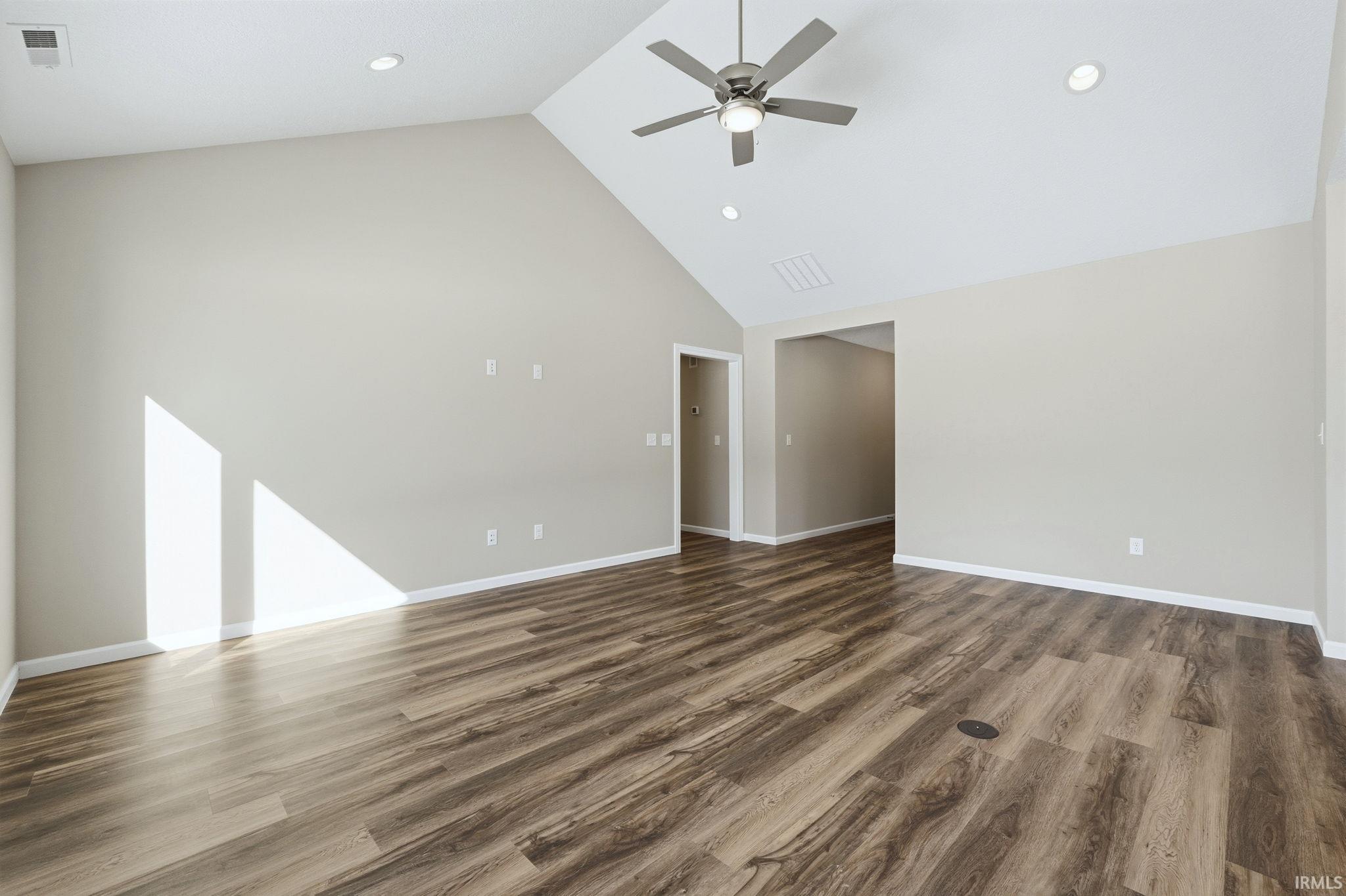 Empty room with a high ceiling, dark wood-style floors, recessed lighting, and a ceiling fan