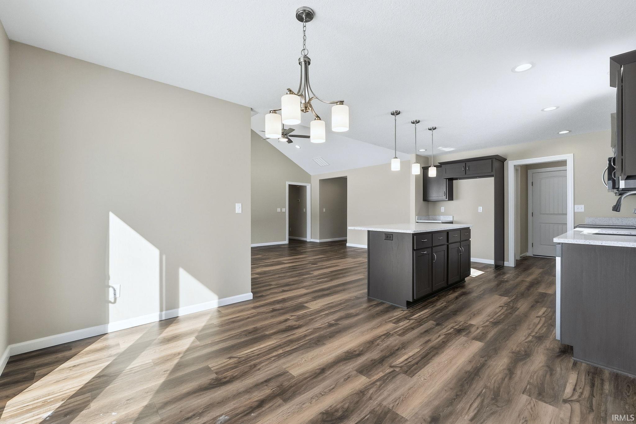 Kitchen featuring open floor plan, hanging lights, dark wood-type flooring, lofted ceiling, and a center island