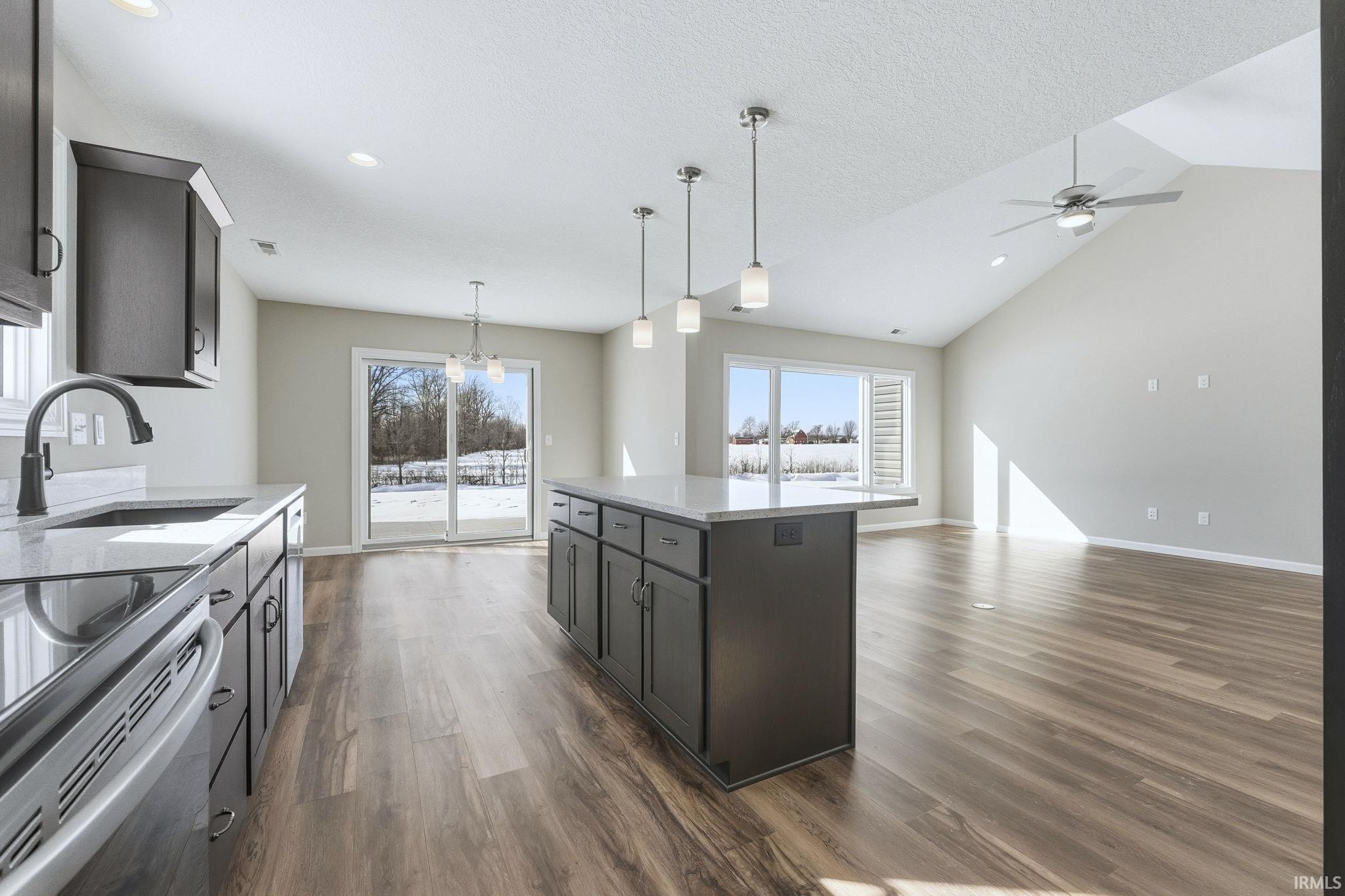 Kitchen featuring light stone counters, open floor plan, dark wood-type flooring, healthy amount of natural light, and a high textured ceiling