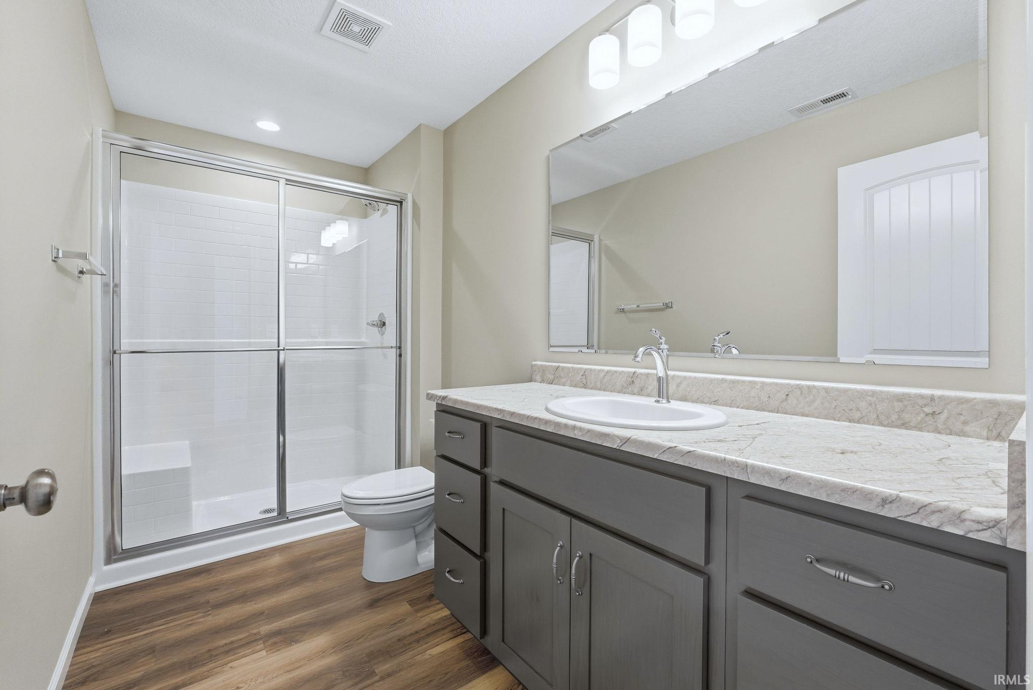 Bathroom with vanity, a shower stall, and dark wood-style flooring