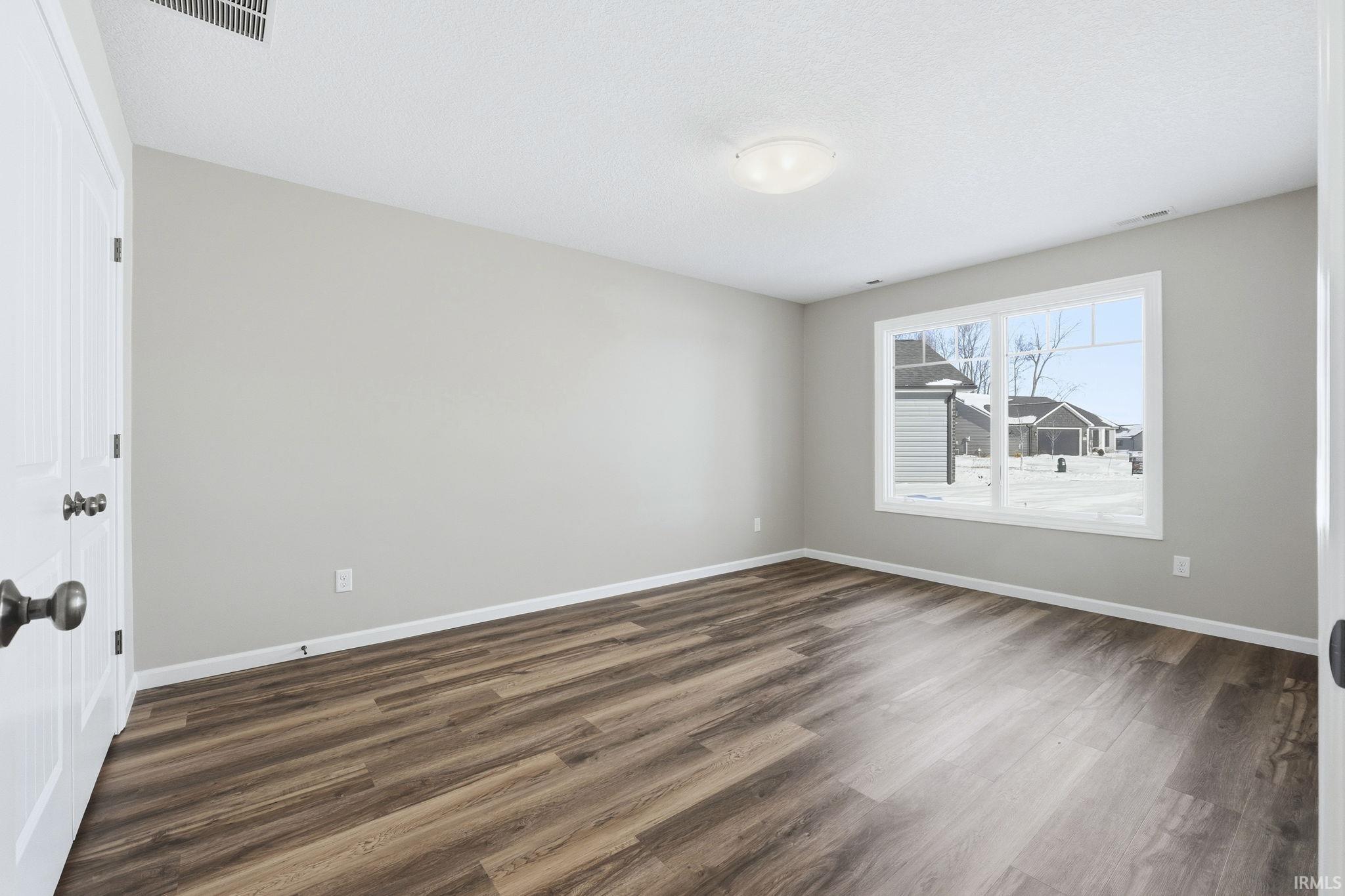 Unfurnished room featuring baseboards and dark wood-style floors