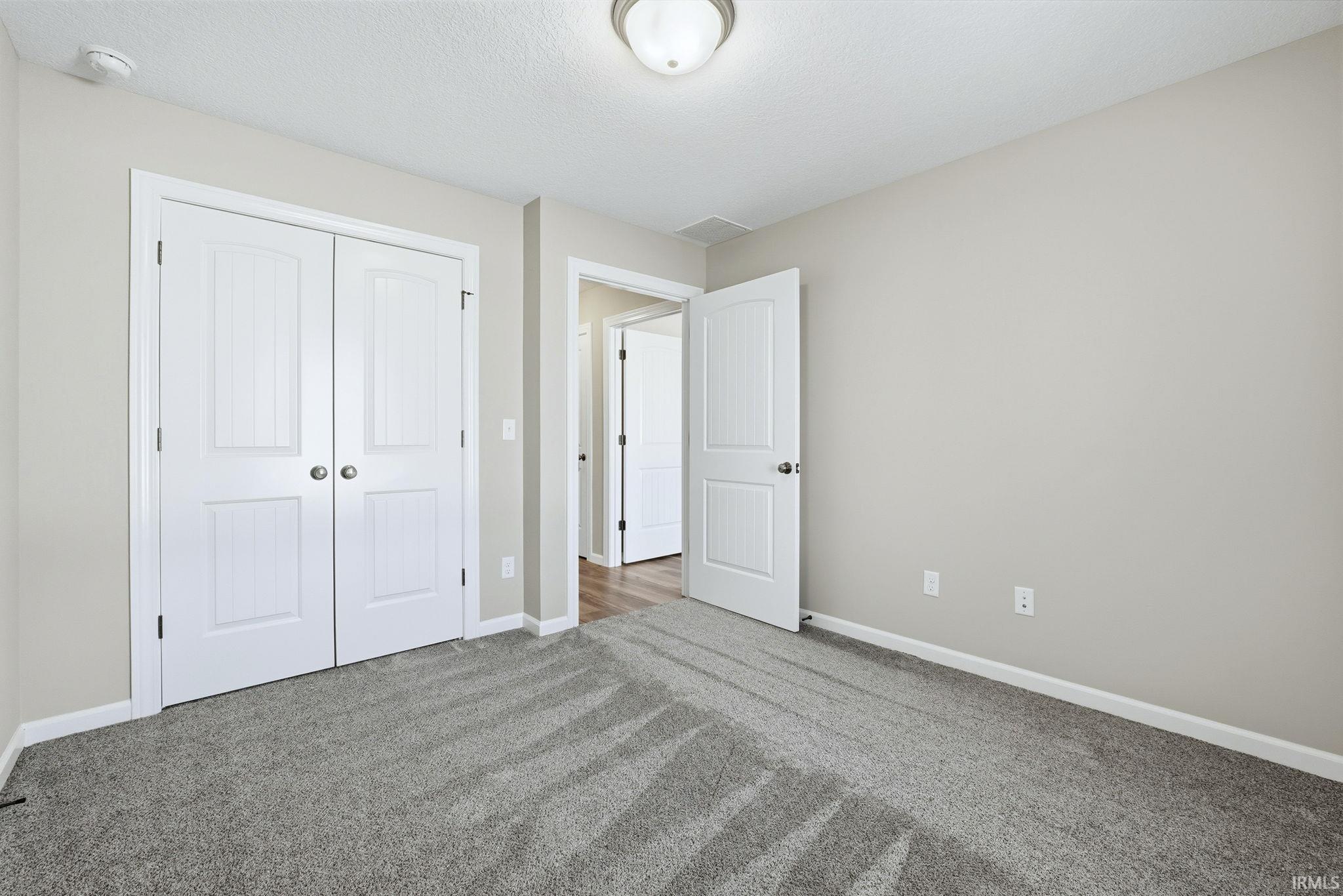 Unfurnished bedroom with carpet floors, a closet, and a textured ceiling
