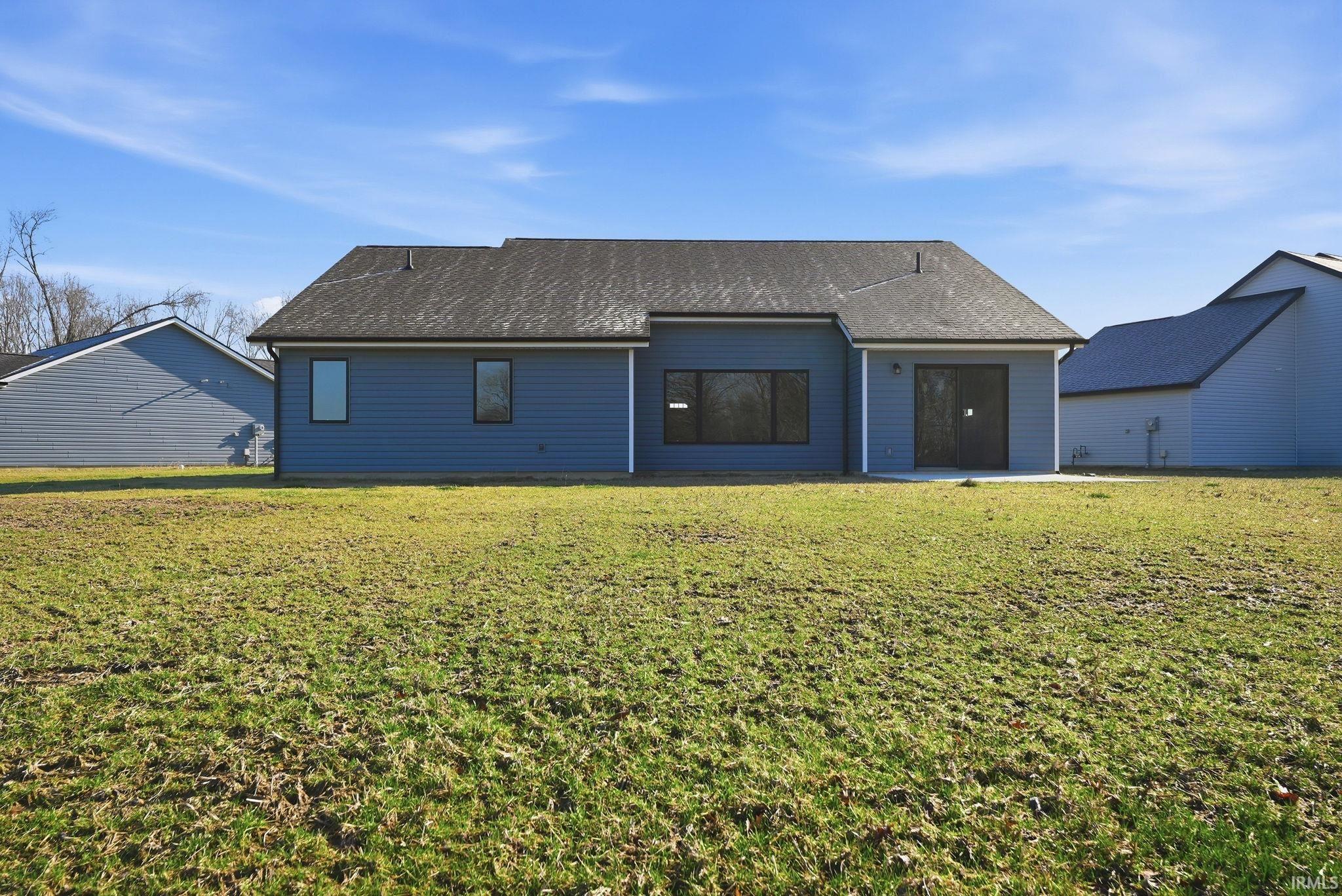 Back of house featuring a shingled roof, a lawn, and a patio