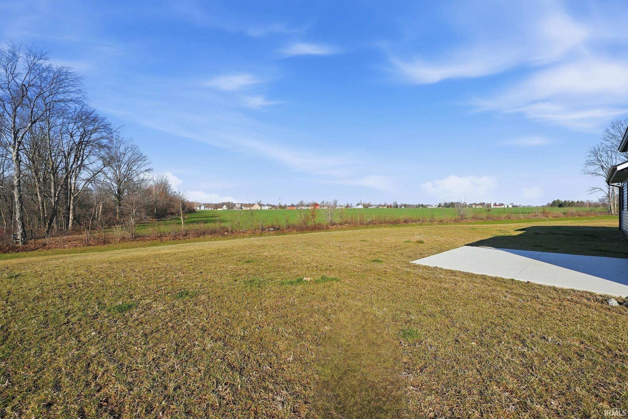 View of green lawn with a view of rural / pastoral area and a patio