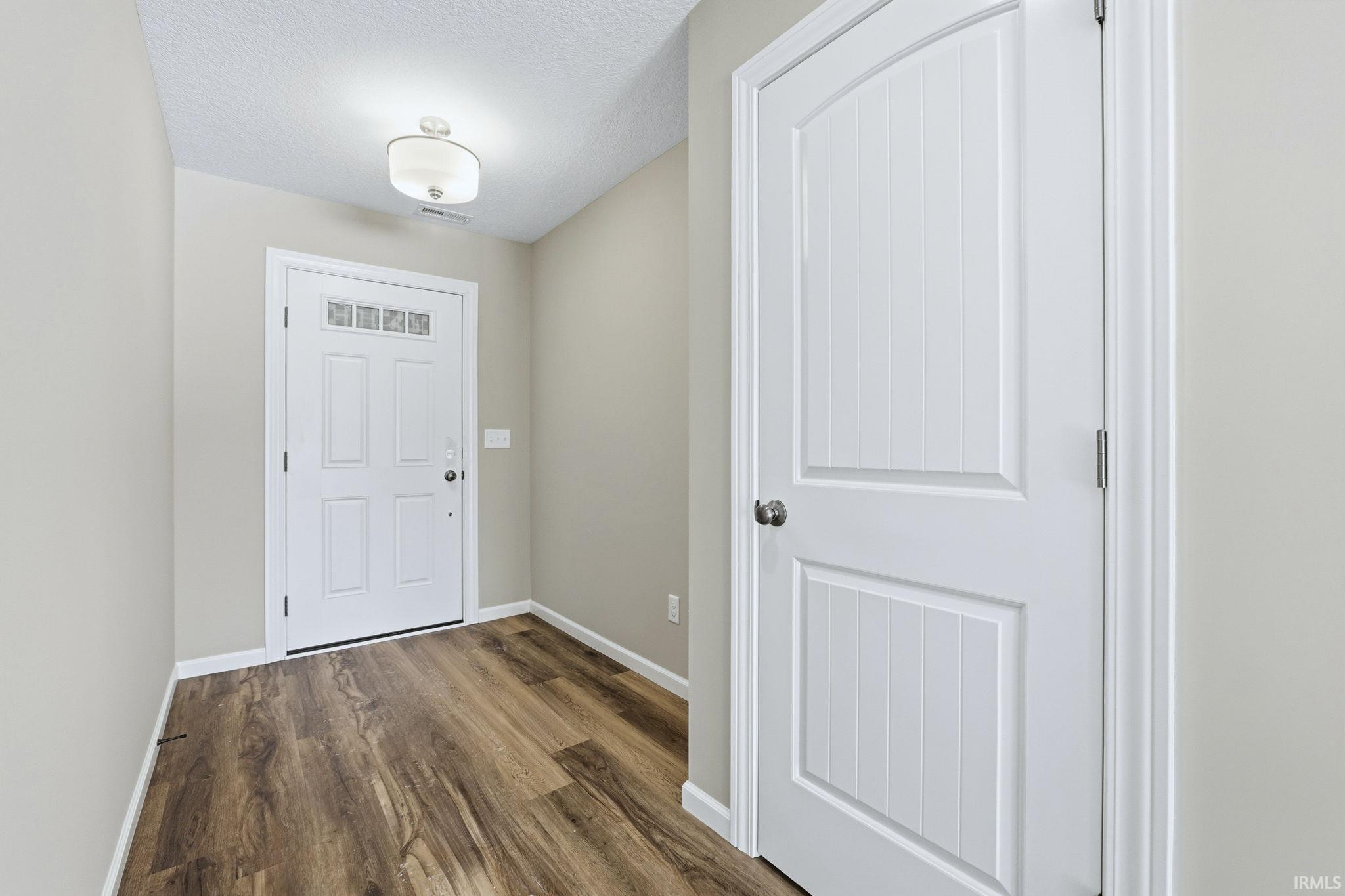 Entryway with a textured ceiling and dark wood finished floors
