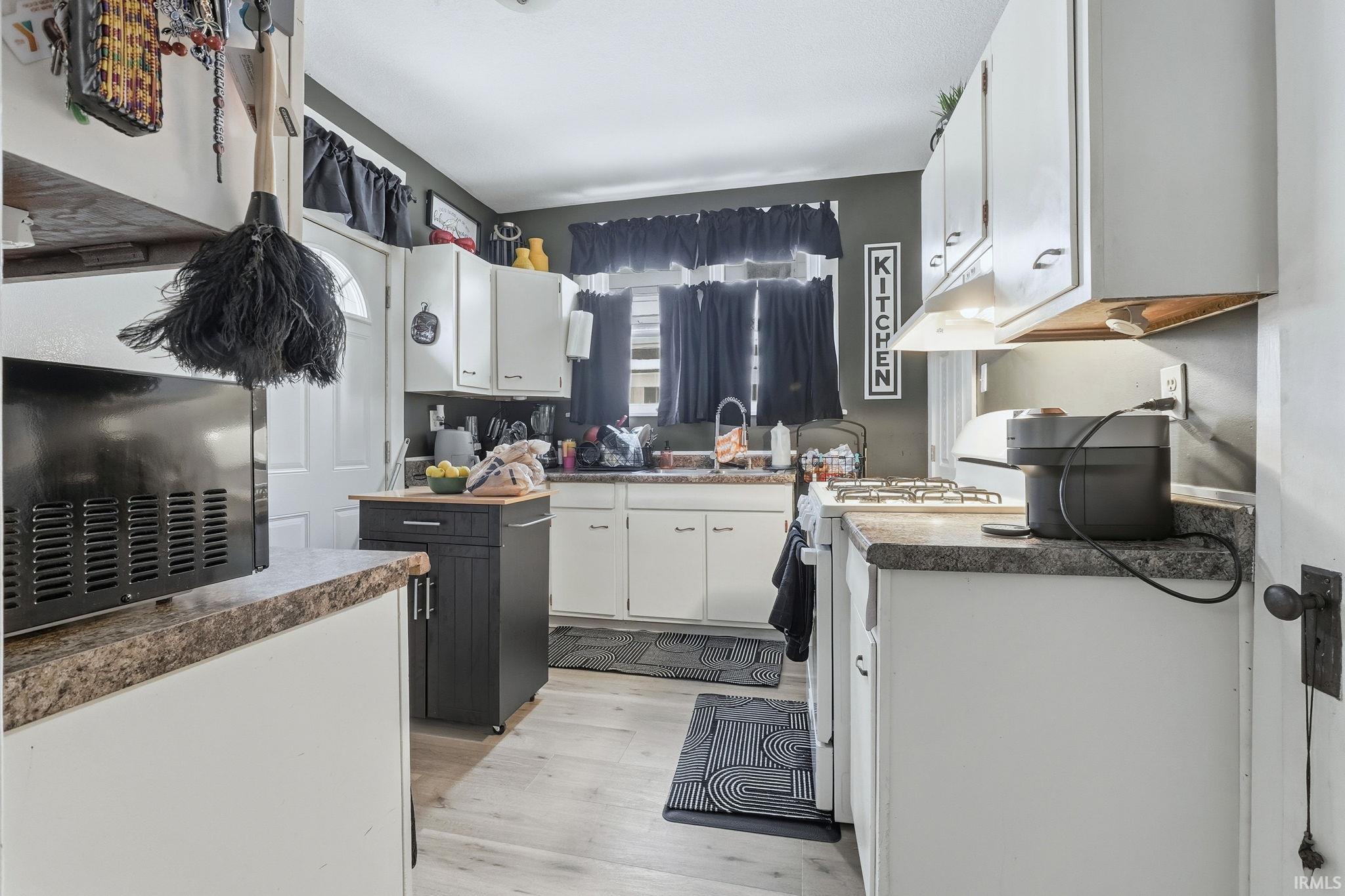 Kitchen featuring white cabinets, white gas range oven, light wood-type flooring, and dark countertops
