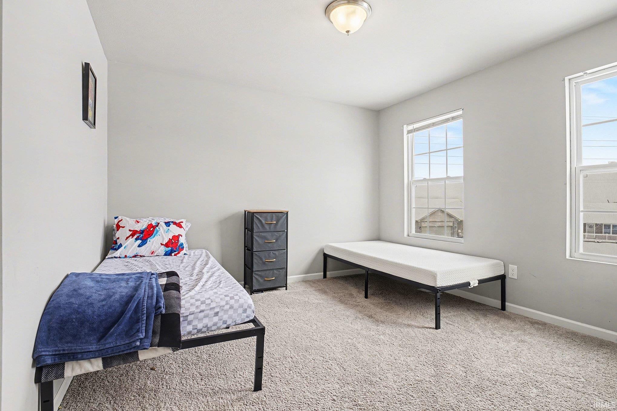 Bedroom with light colored carpet and baseboards
