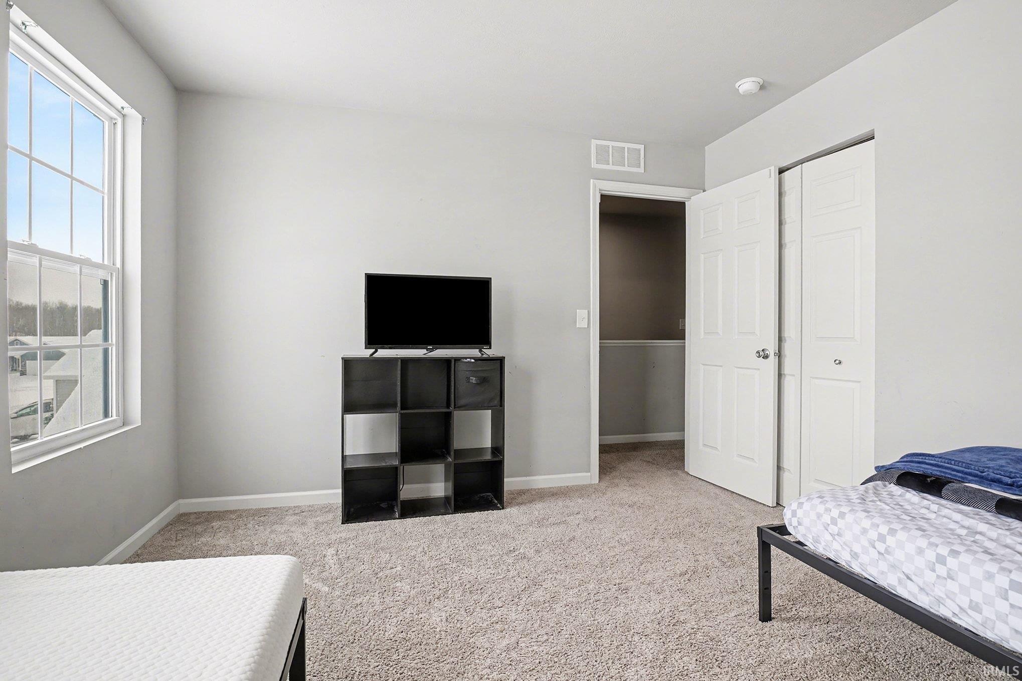 Bedroom featuring light carpet and a closet