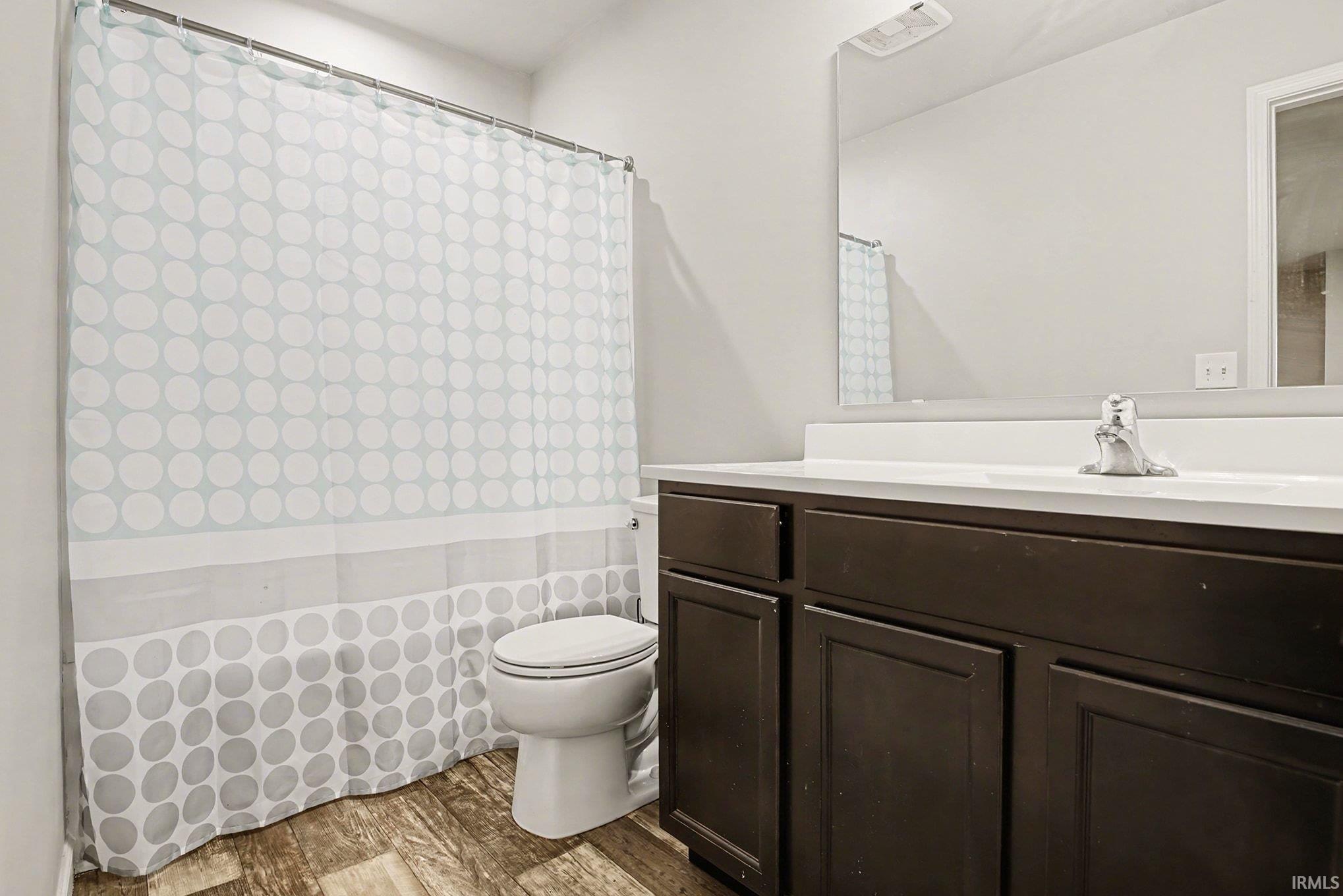 Full bathroom with vanity, curtained shower, and dark wood-style floors