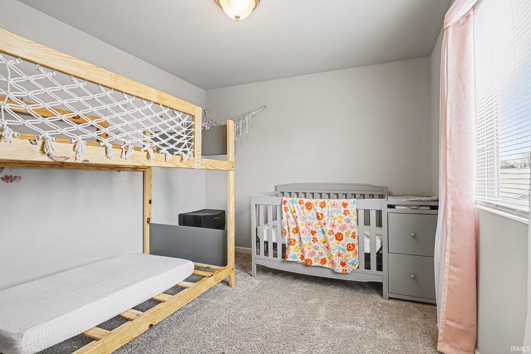 Bedroom with a crib and light carpet