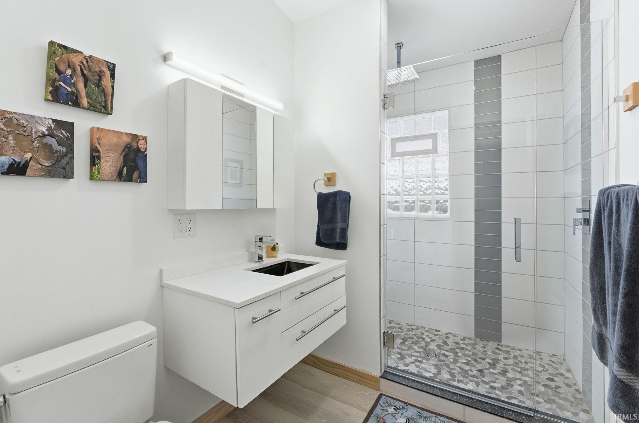 Full bath featuring vanity, a shower stall, and light wood-type flooring