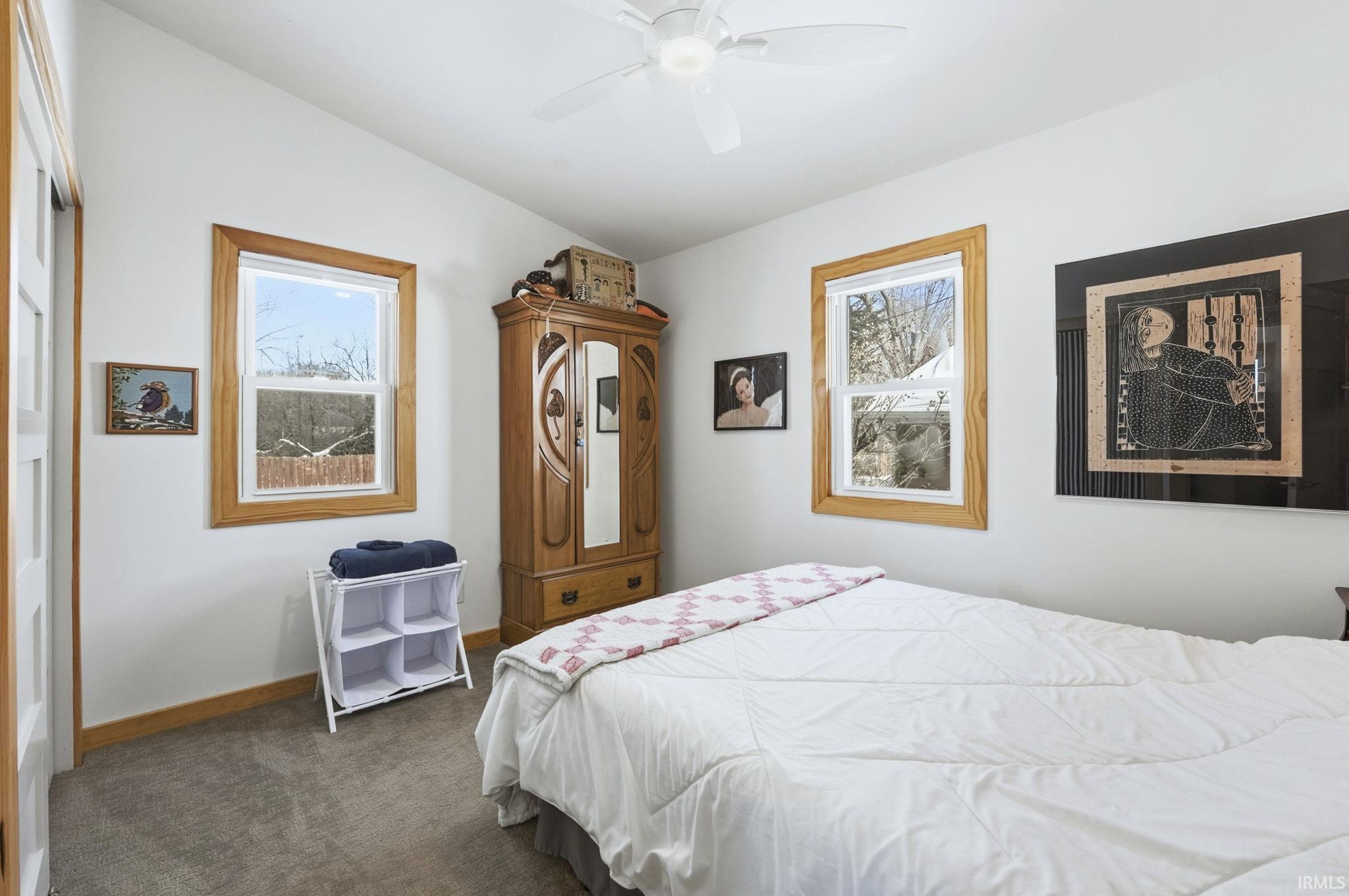 Carpeted bedroom with lofted ceiling and a ceiling fan