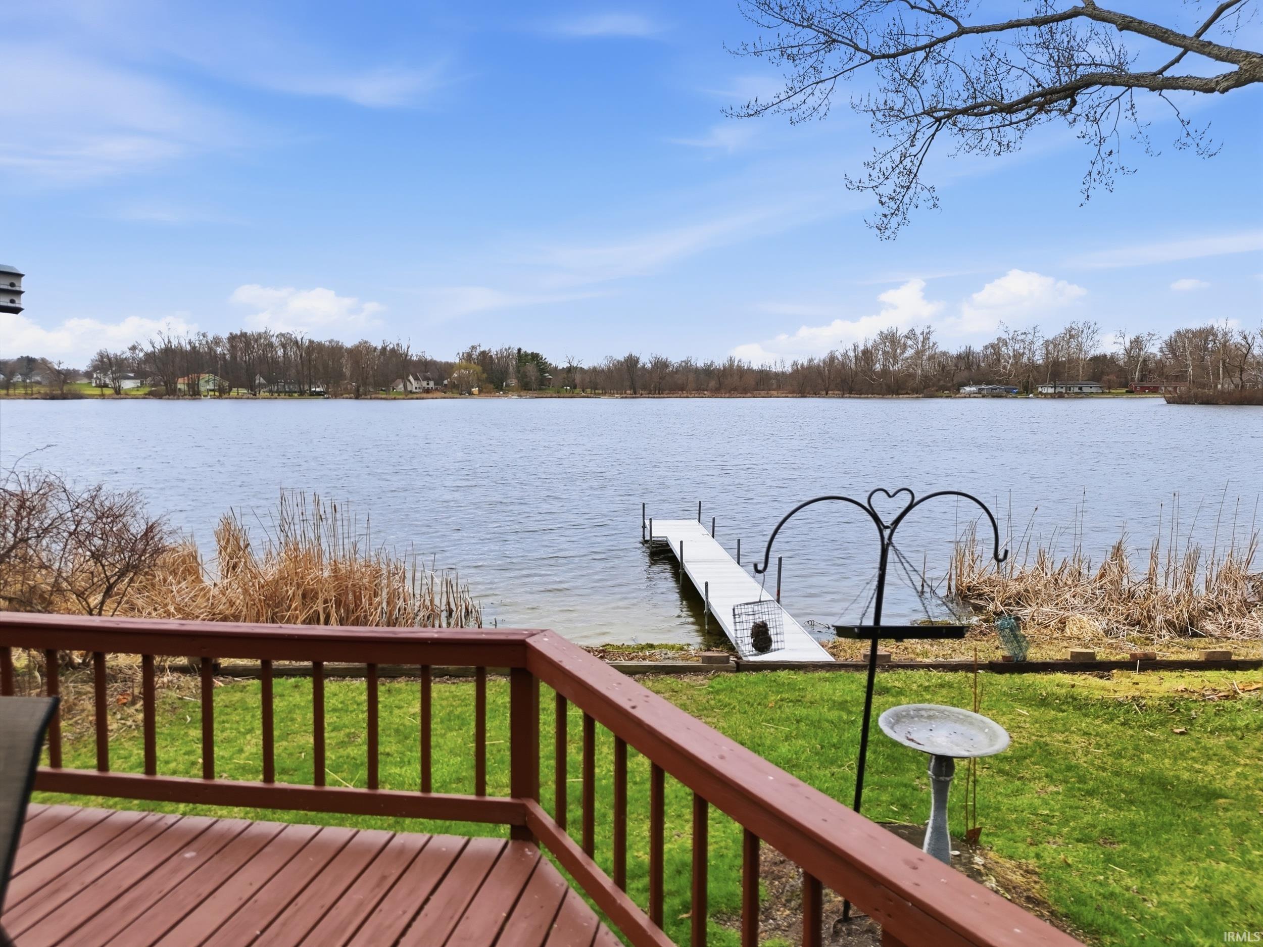 Wooden terrace featuring a boat dock, a water view, and a yard