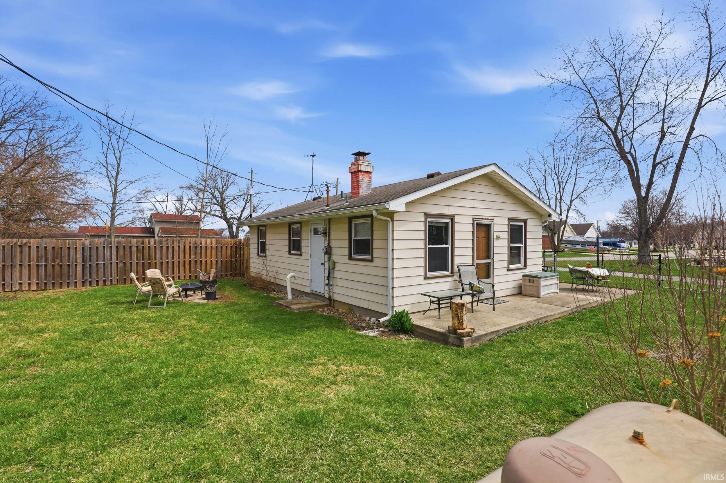 Rear view of house featuring a fenced backyard, a patio area, a chimney, and a fire pit